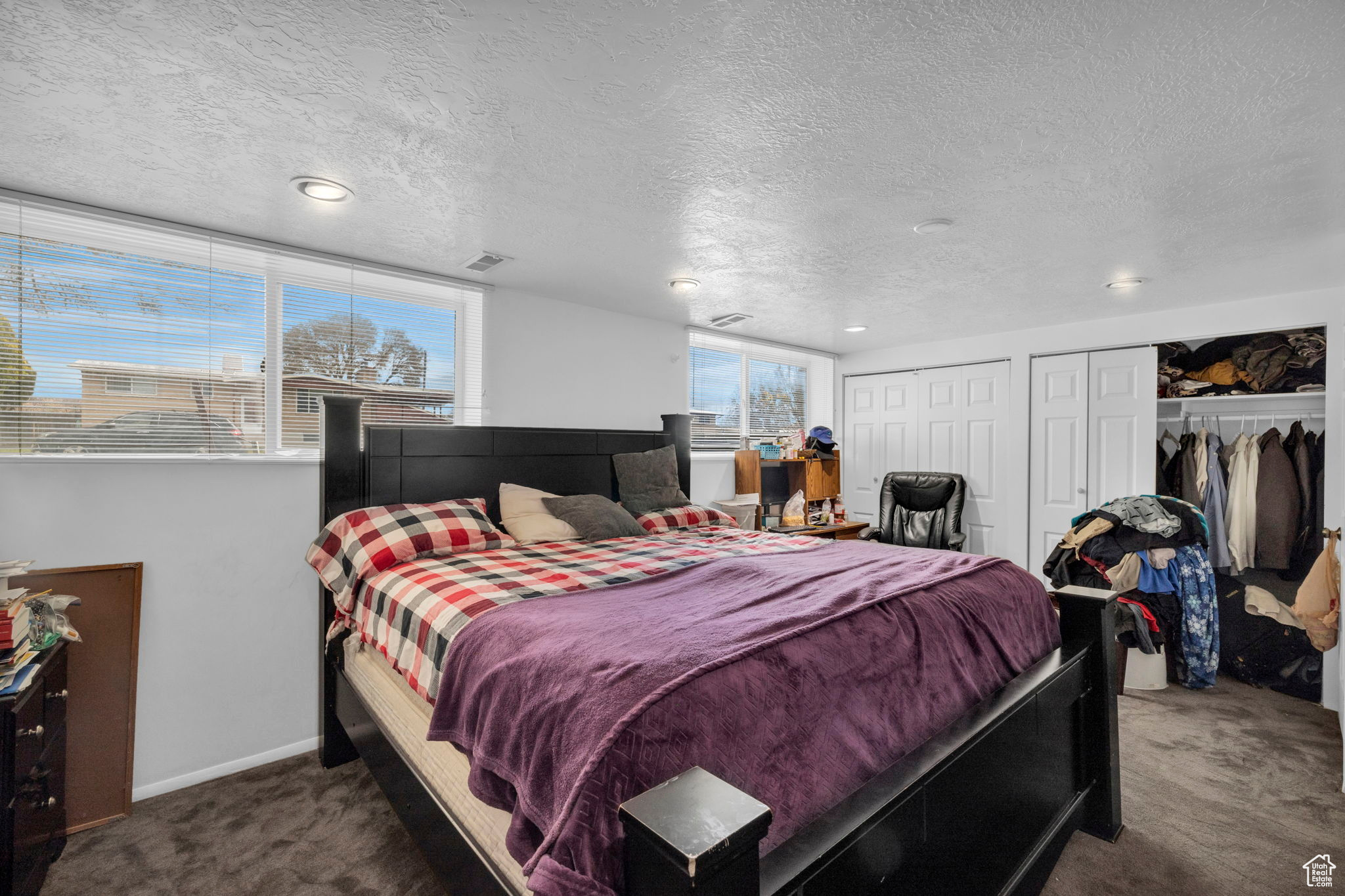 Bedroom with multiple closets, dark carpet, and a textured ceiling