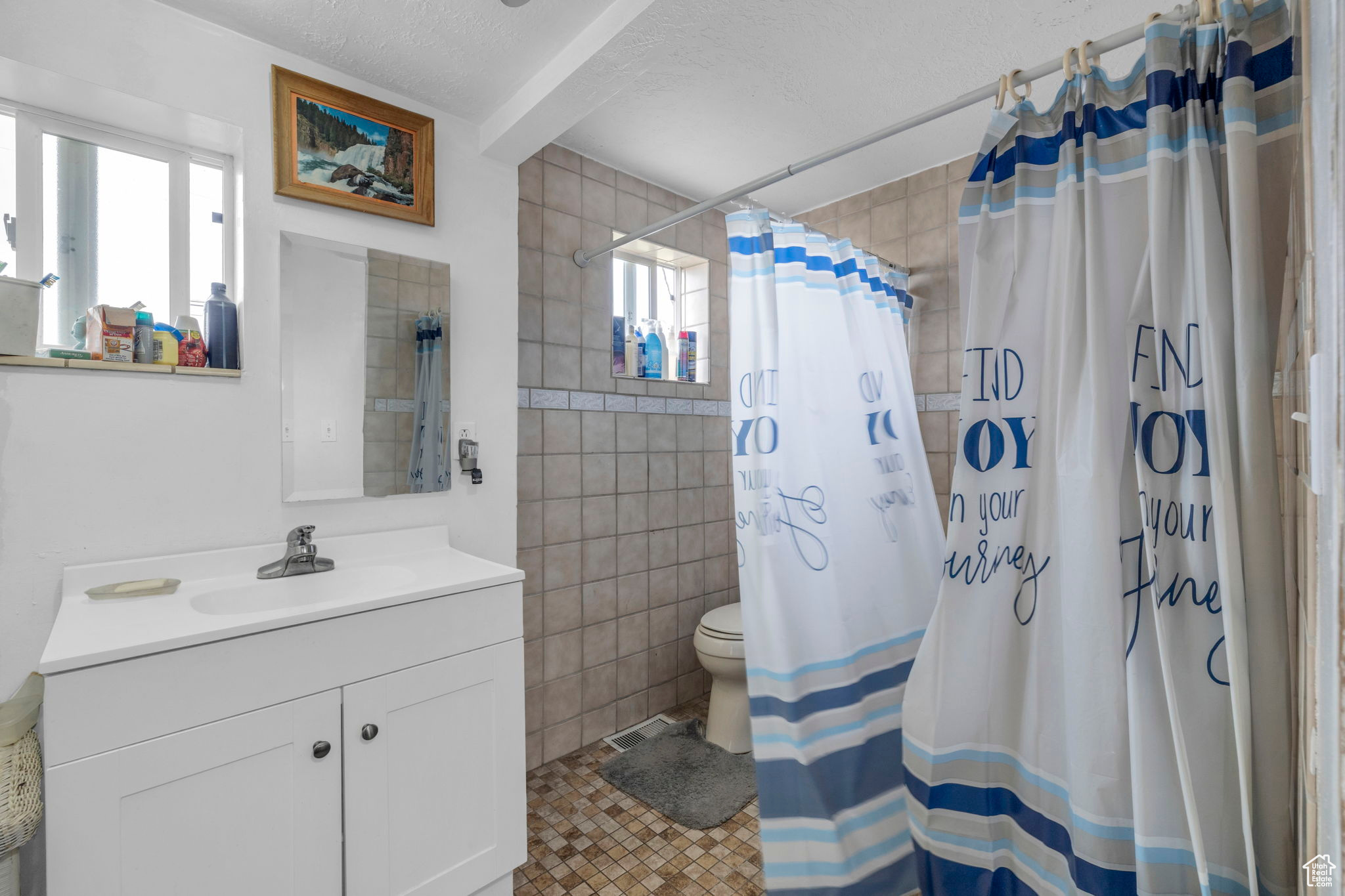 Bathroom with a shower with curtain, a textured ceiling, vanity, and tile walls