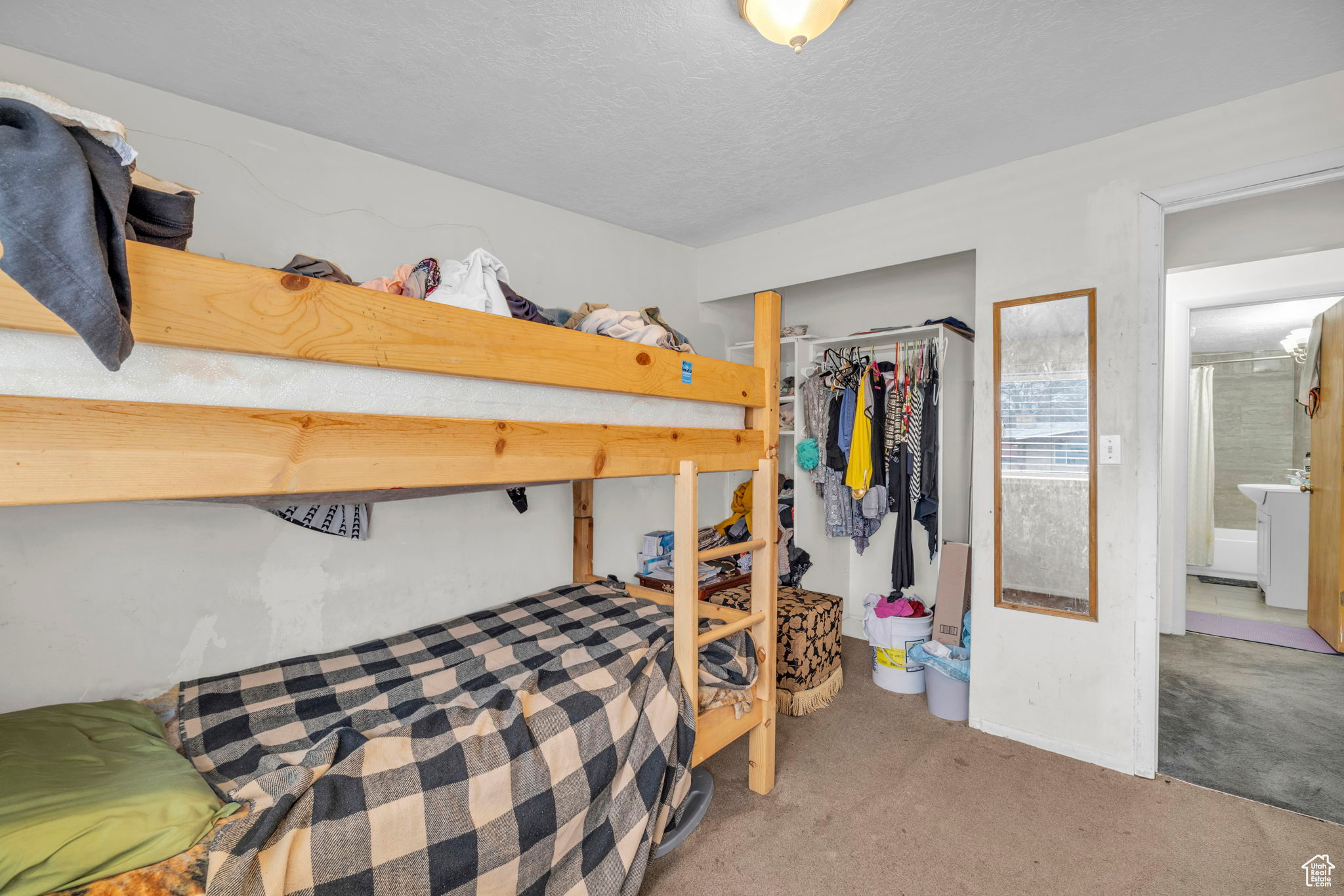 Carpeted bedroom featuring a textured ceiling and a closet