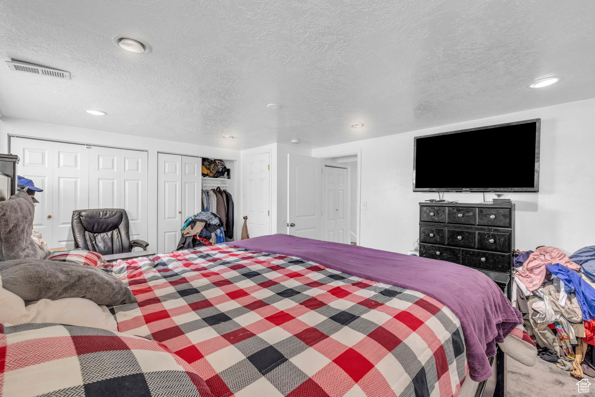 Bedroom with multiple closets, carpet, and a textured ceiling