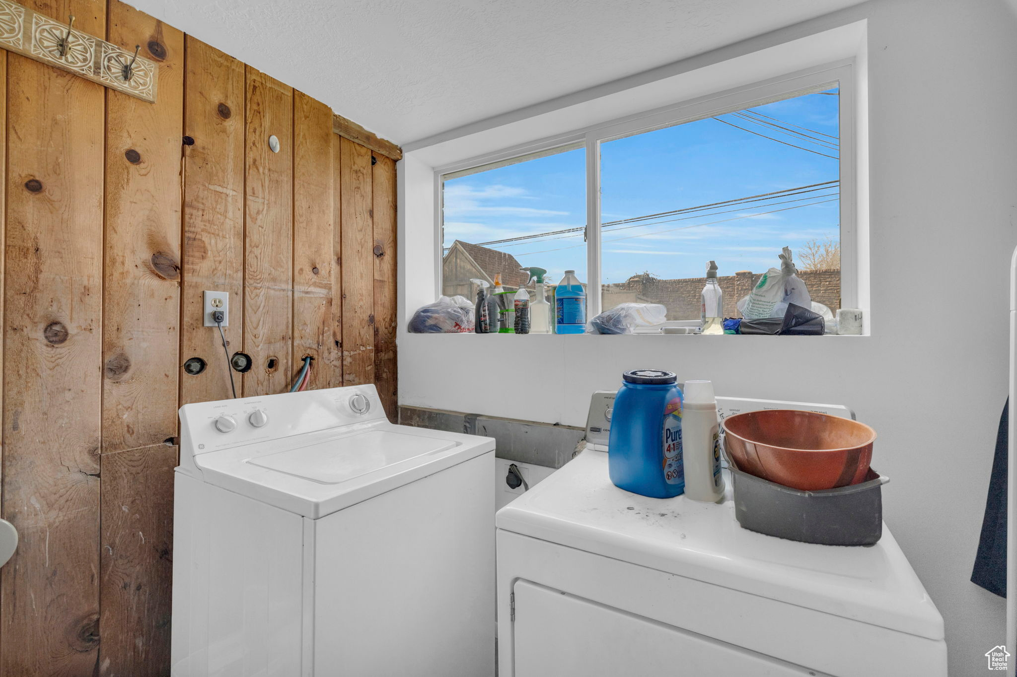 Clothes washing area featuring washing machine and dryer and wooden walls