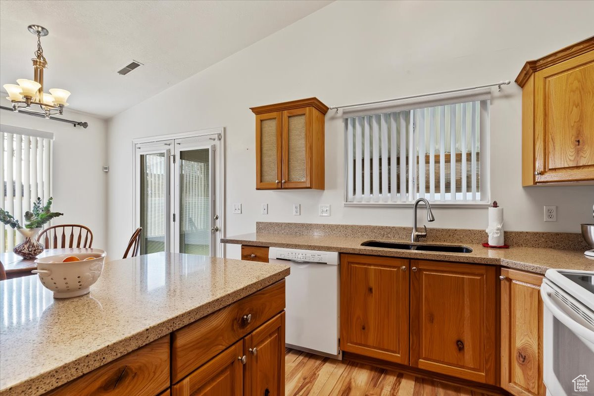 Kitchen with pendant lighting, lofted ceiling, white appliances, sink, and a chandelier