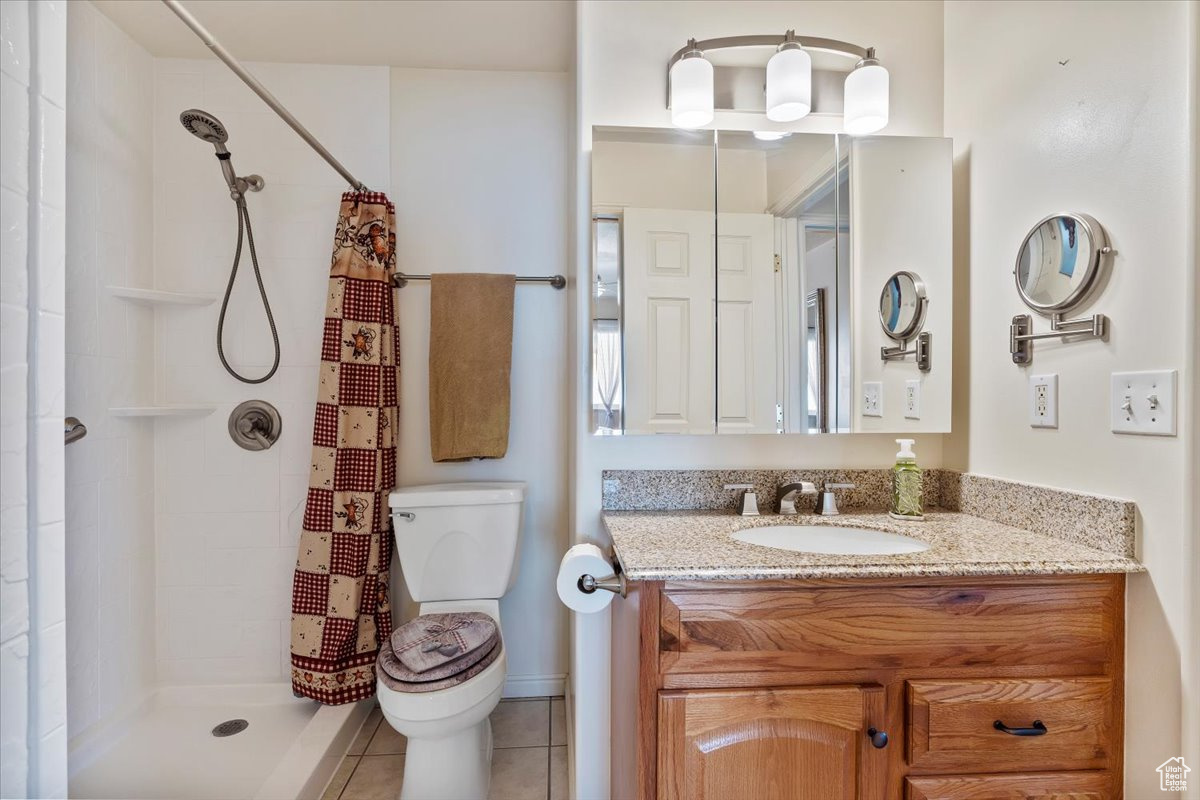 Bathroom with tile patterned flooring, vanity, toilet, and curtained shower