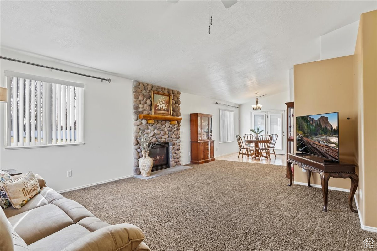 Living room with a fireplace, carpet floors, vaulted ceiling, and ceiling fan