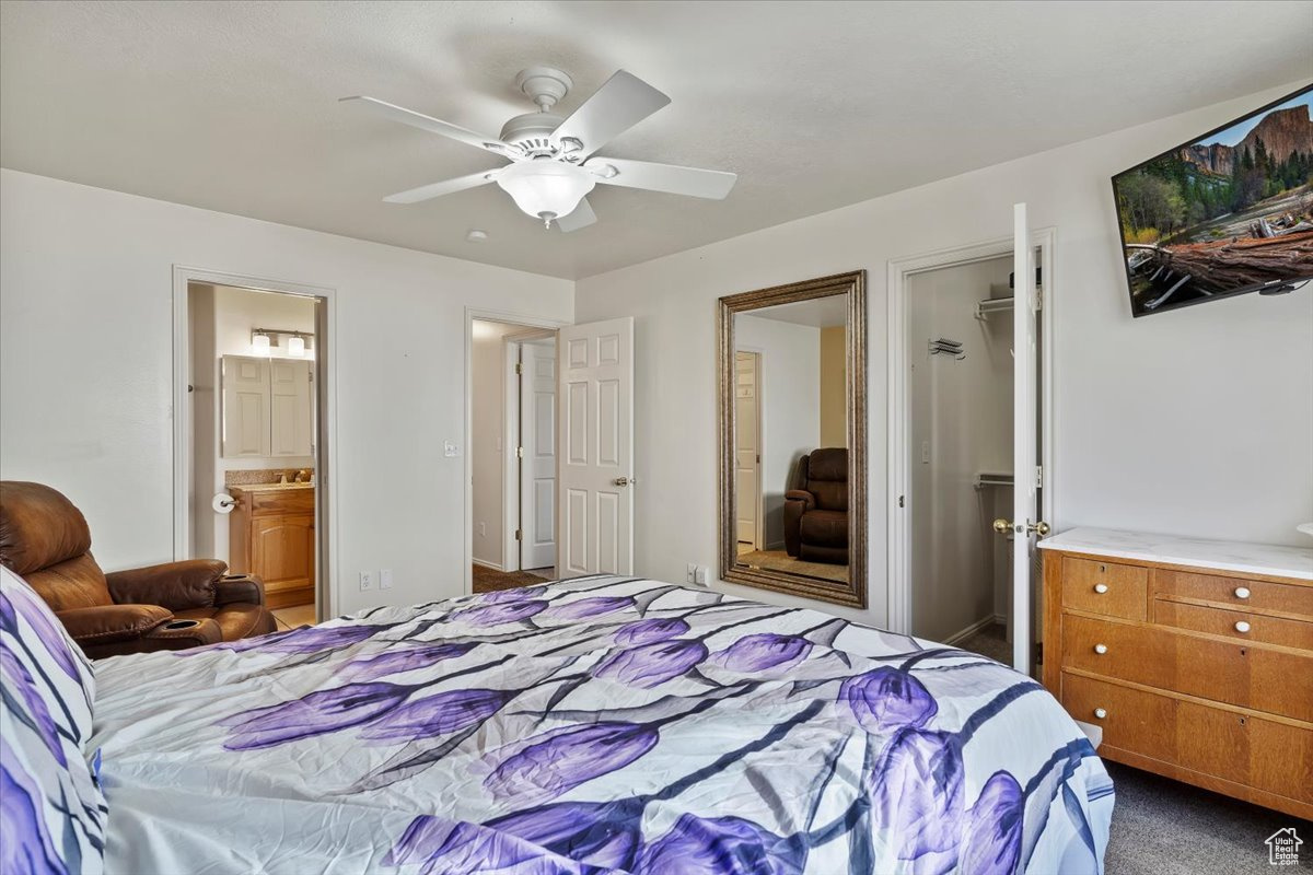 Carpeted bedroom featuring ensuite bathroom, a closet, and ceiling fan