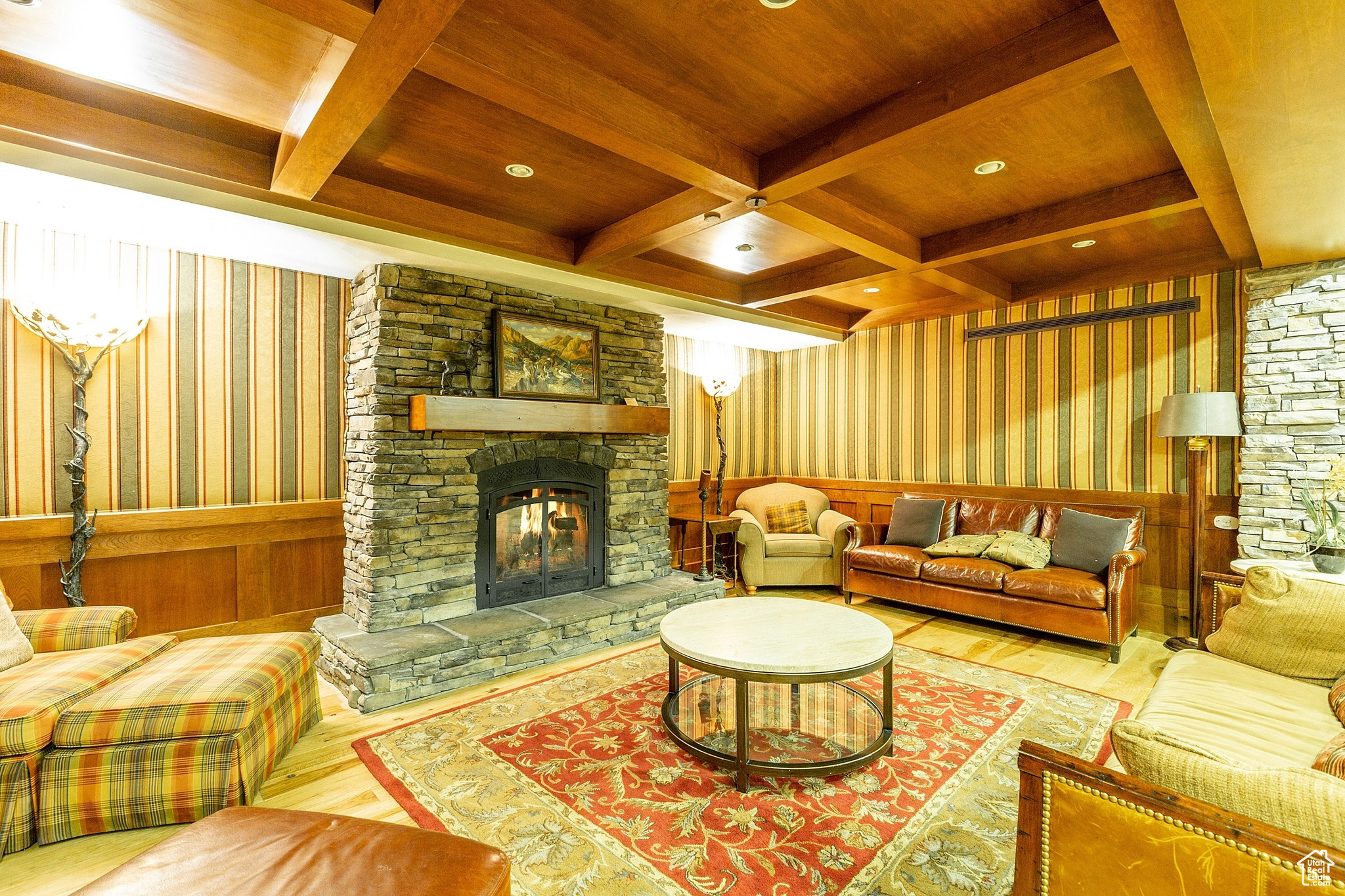 Living room with hardwood / wood-style floors, coffered ceiling, a stone fireplace, beam ceiling, and wood ceiling