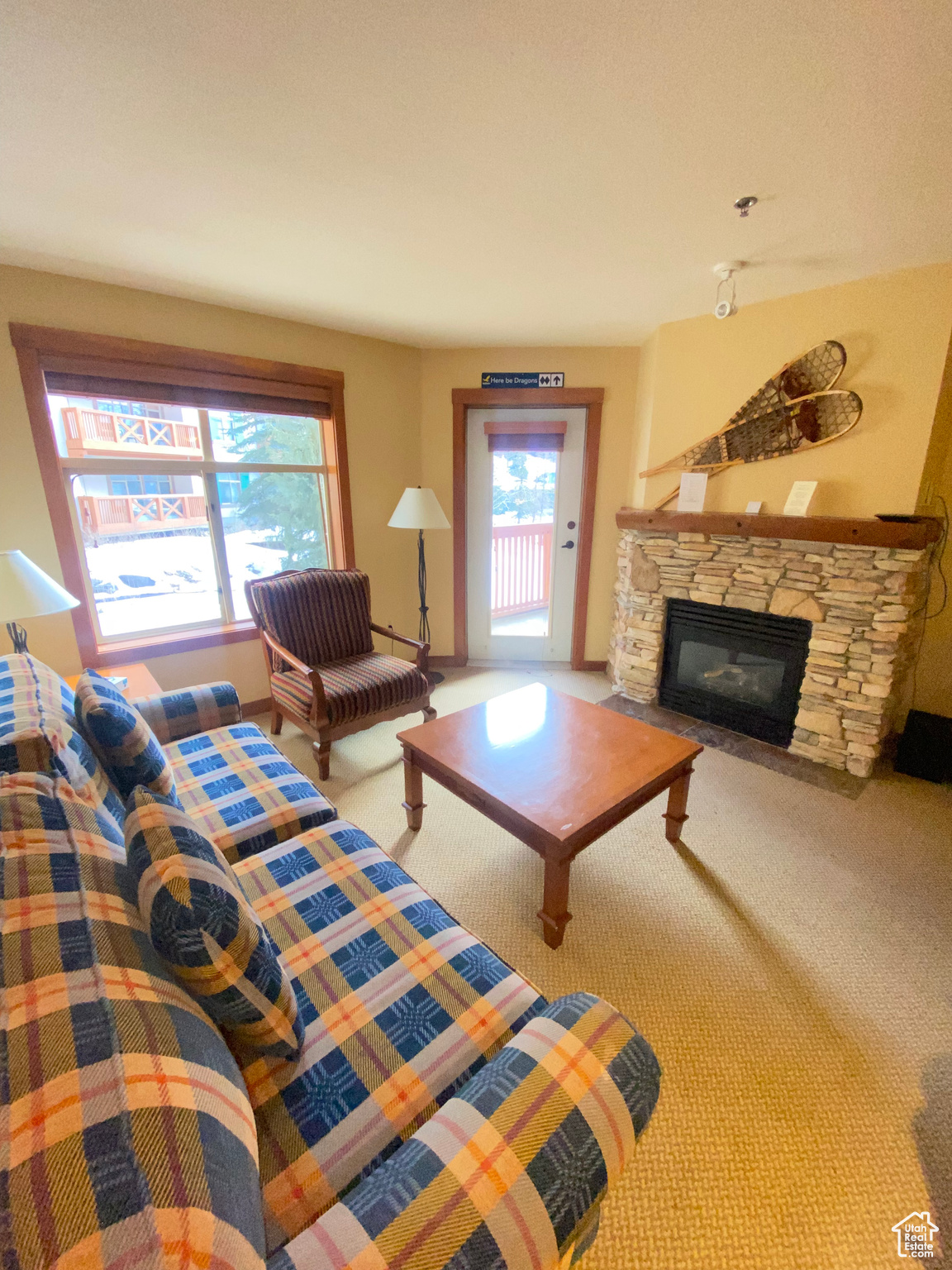 Carpeted living room featuring a stone fireplace