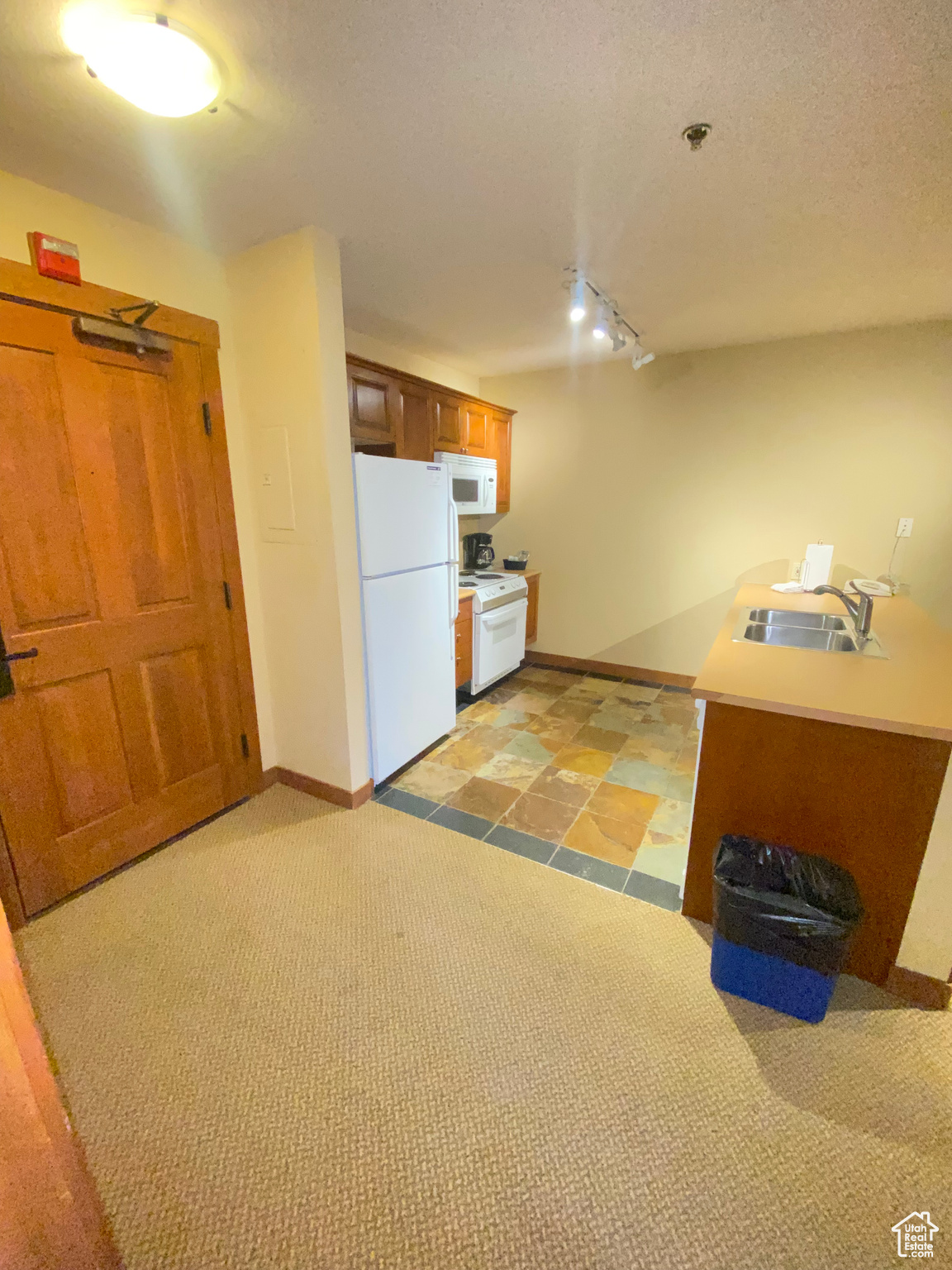 Kitchen with white appliances, rail lighting, and sink