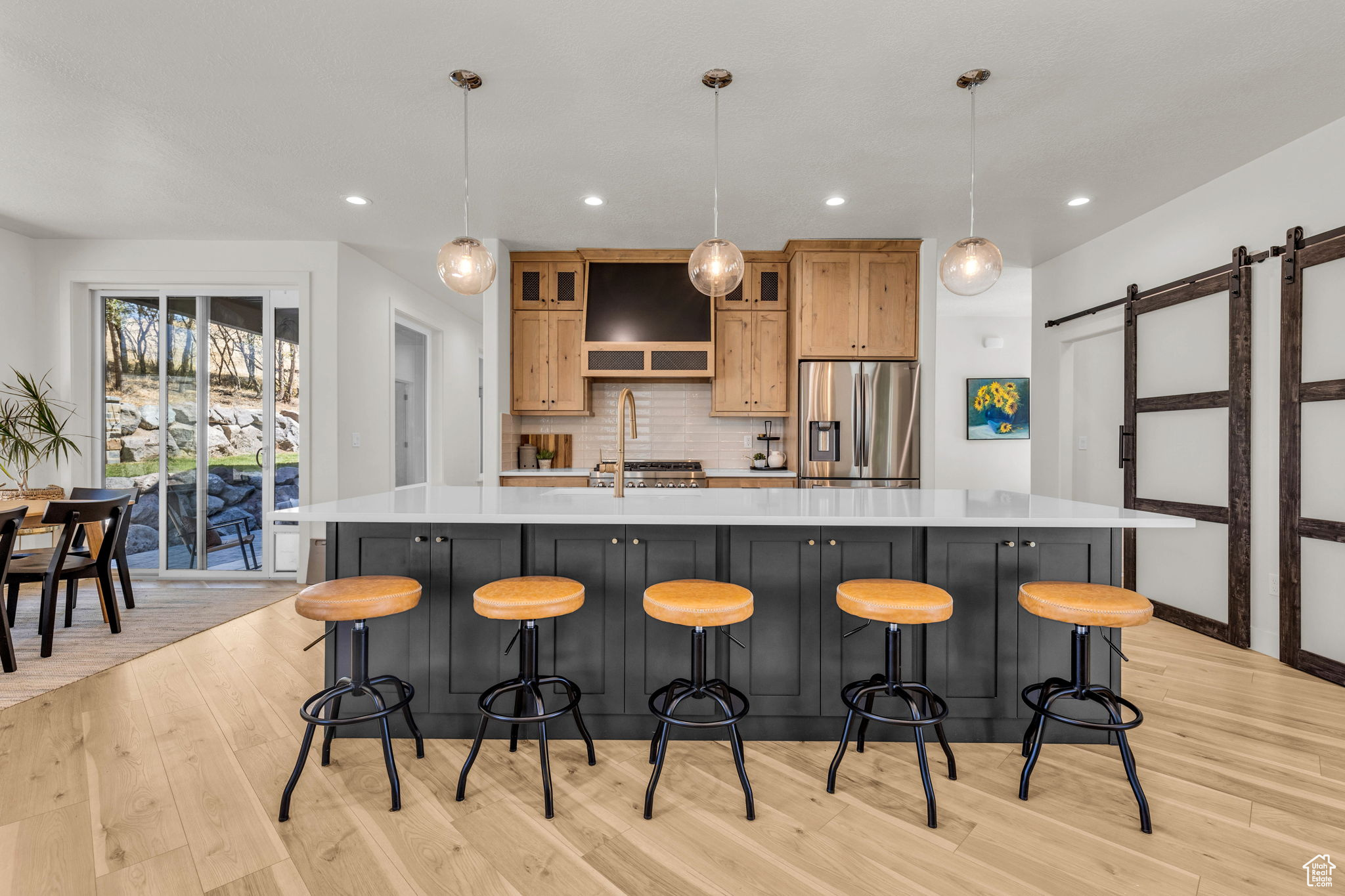 Kitchen featuring stainless steel fridge, a large island, a barn door, and pendant lighting