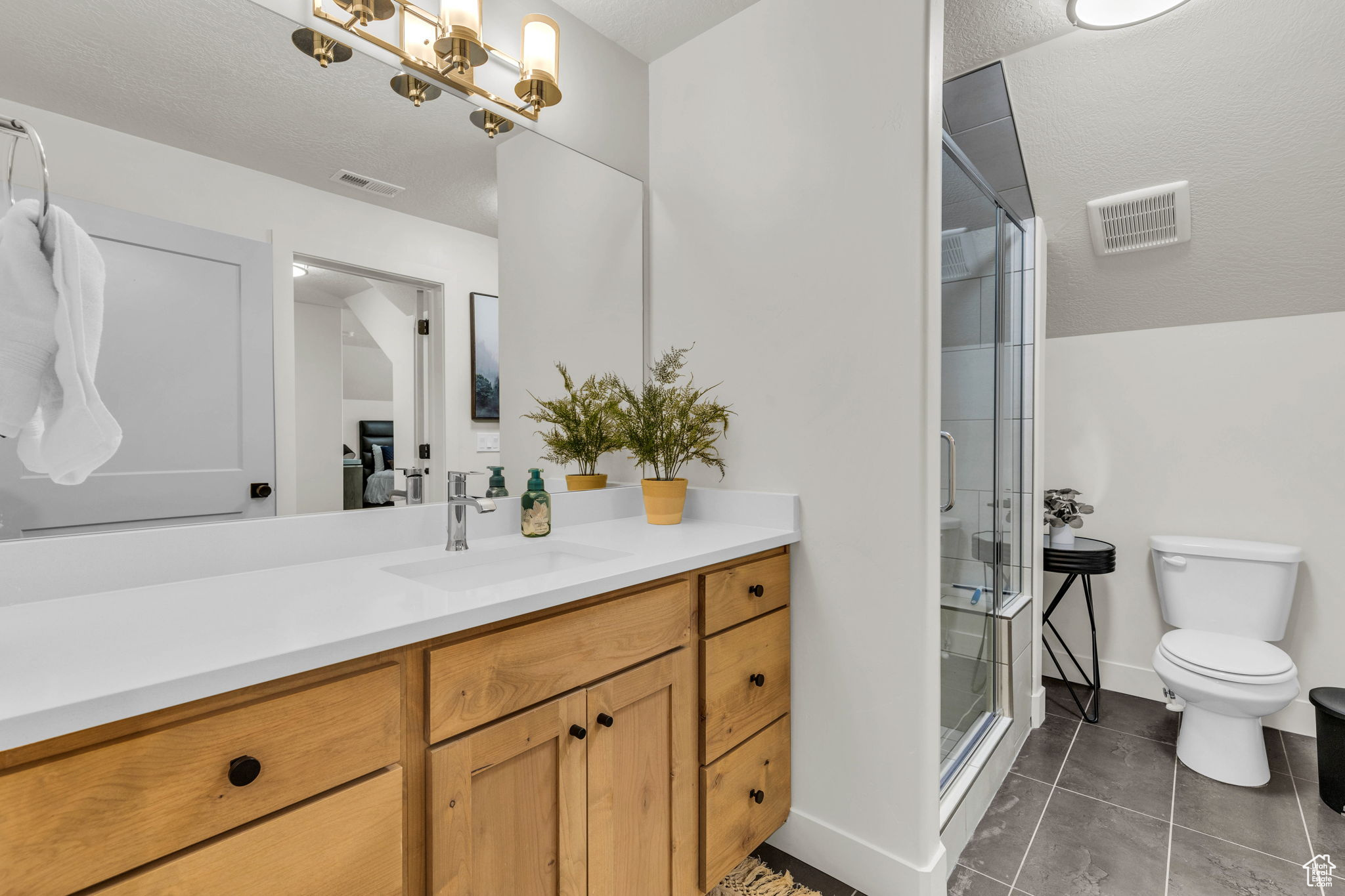 Bathroom with vanity, a shower with door, tile patterned floors, toilet, and a textured ceiling