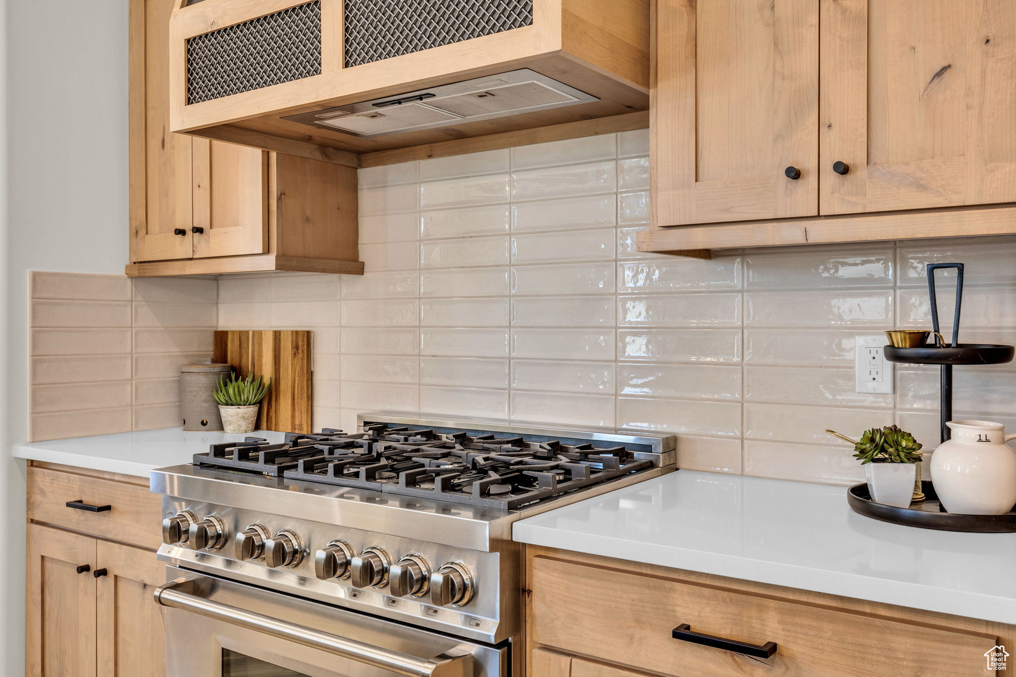 Kitchen with backsplash, light brown cabinetry, high end stainless steel range oven, and extractor fan