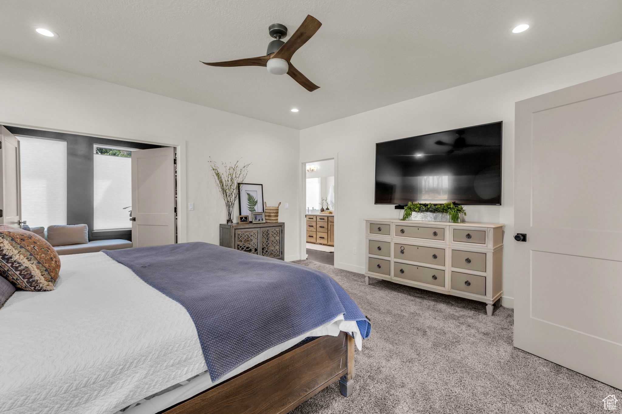 Carpeted bedroom featuring connected bathroom and ceiling fan