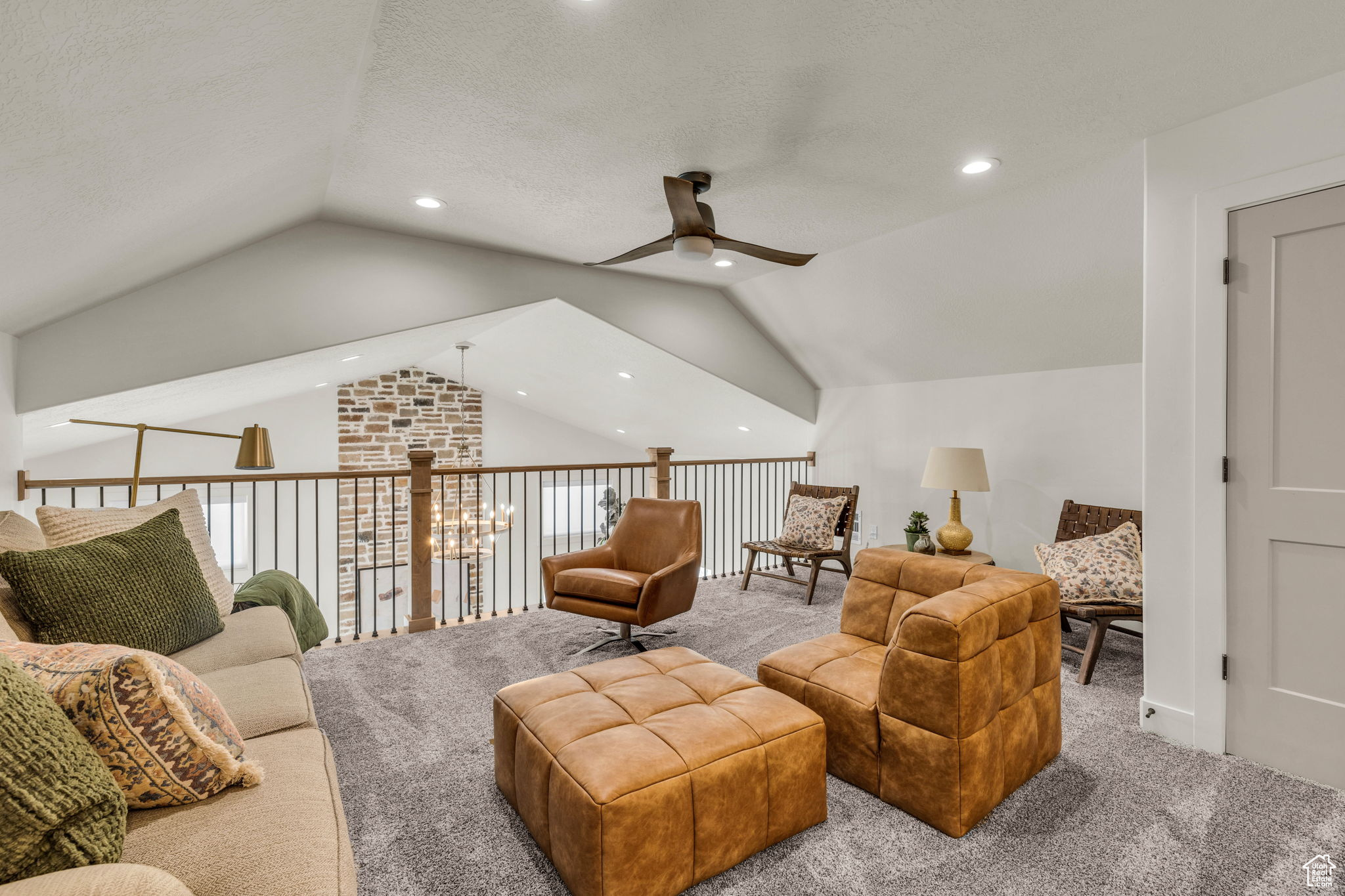 Living room with light carpet, a textured ceiling, vaulted ceiling, and ceiling fan