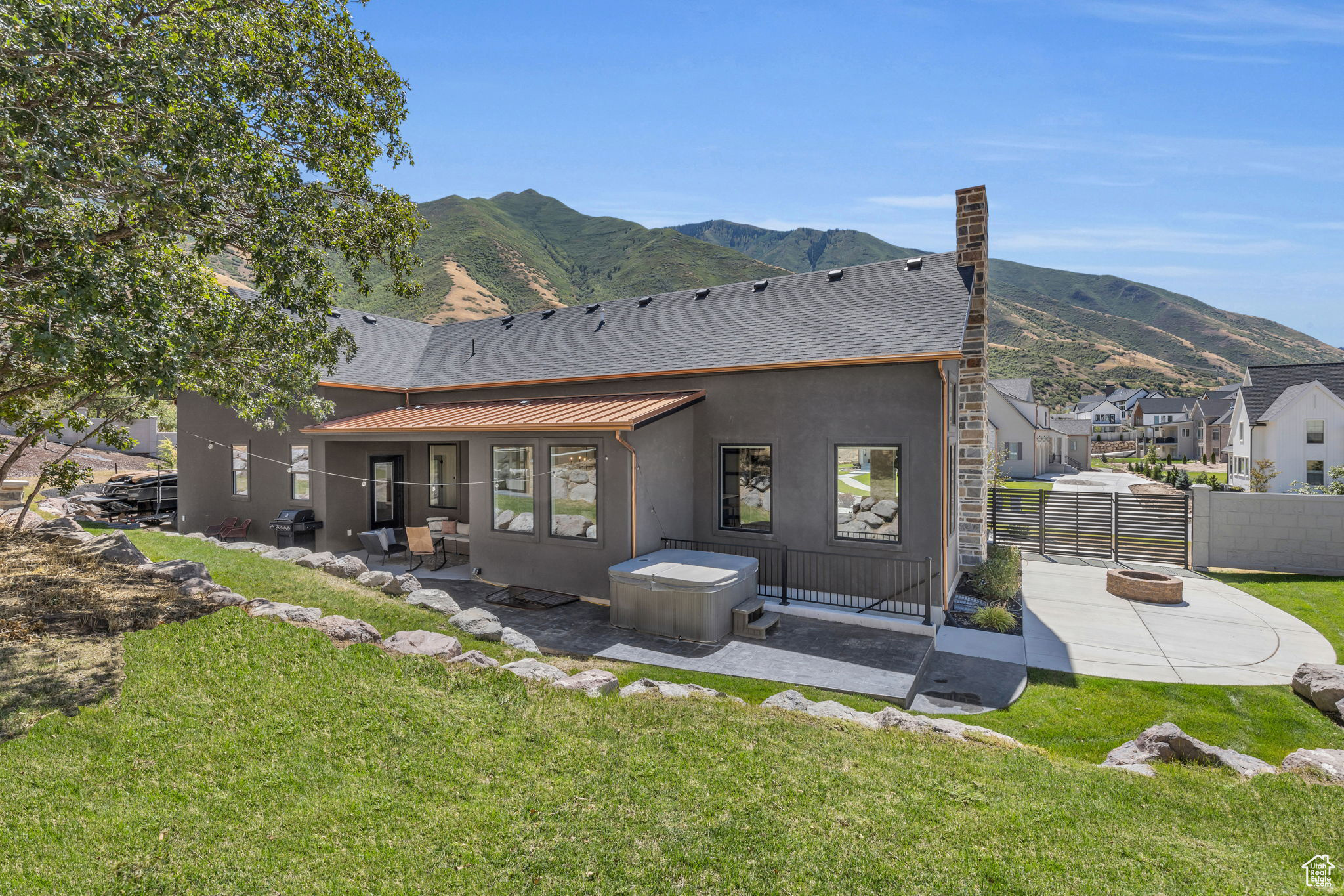 Rear view of house with a mountain view, an outdoor fire pit, a patio area, and a lawn