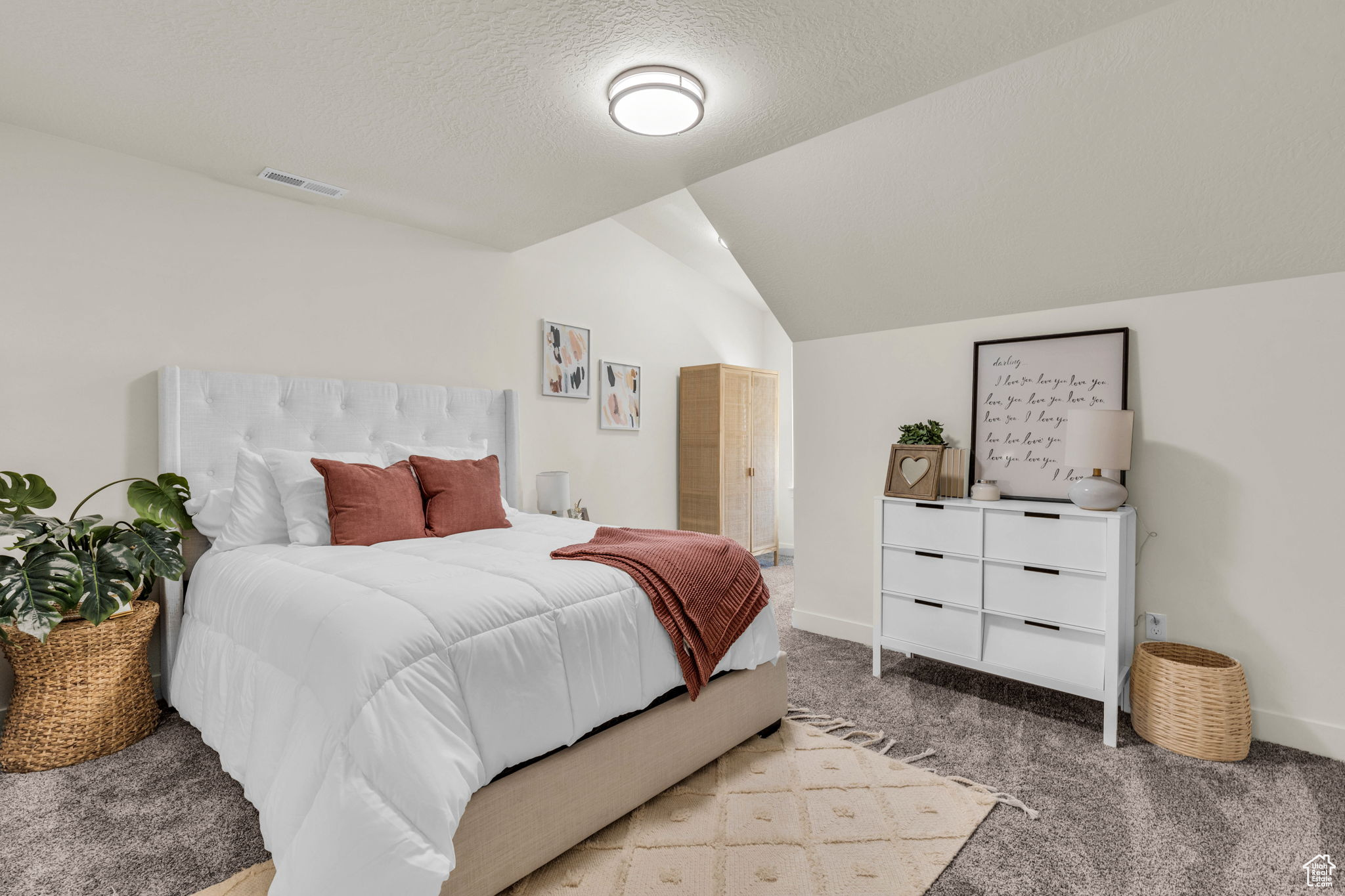 Carpeted bedroom featuring a textured ceiling and lofted ceiling