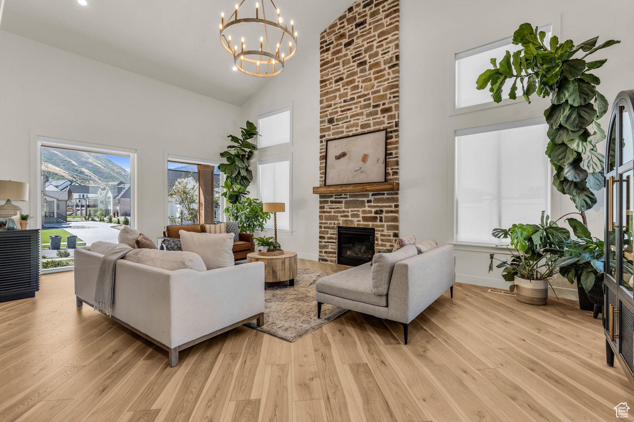 Living room with a fireplace, high vaulted ceiling, a chandelier, and light hardwood / wood-style floors