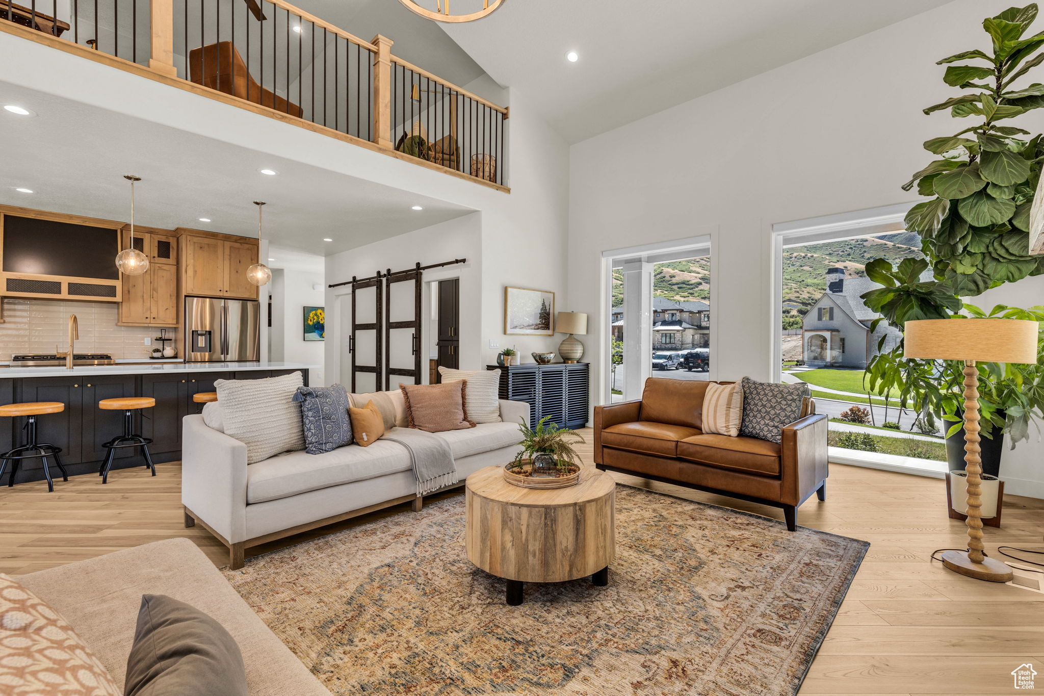 Living room featuring a towering ceiling, a barn door, and light hardwood / wood-style flooring