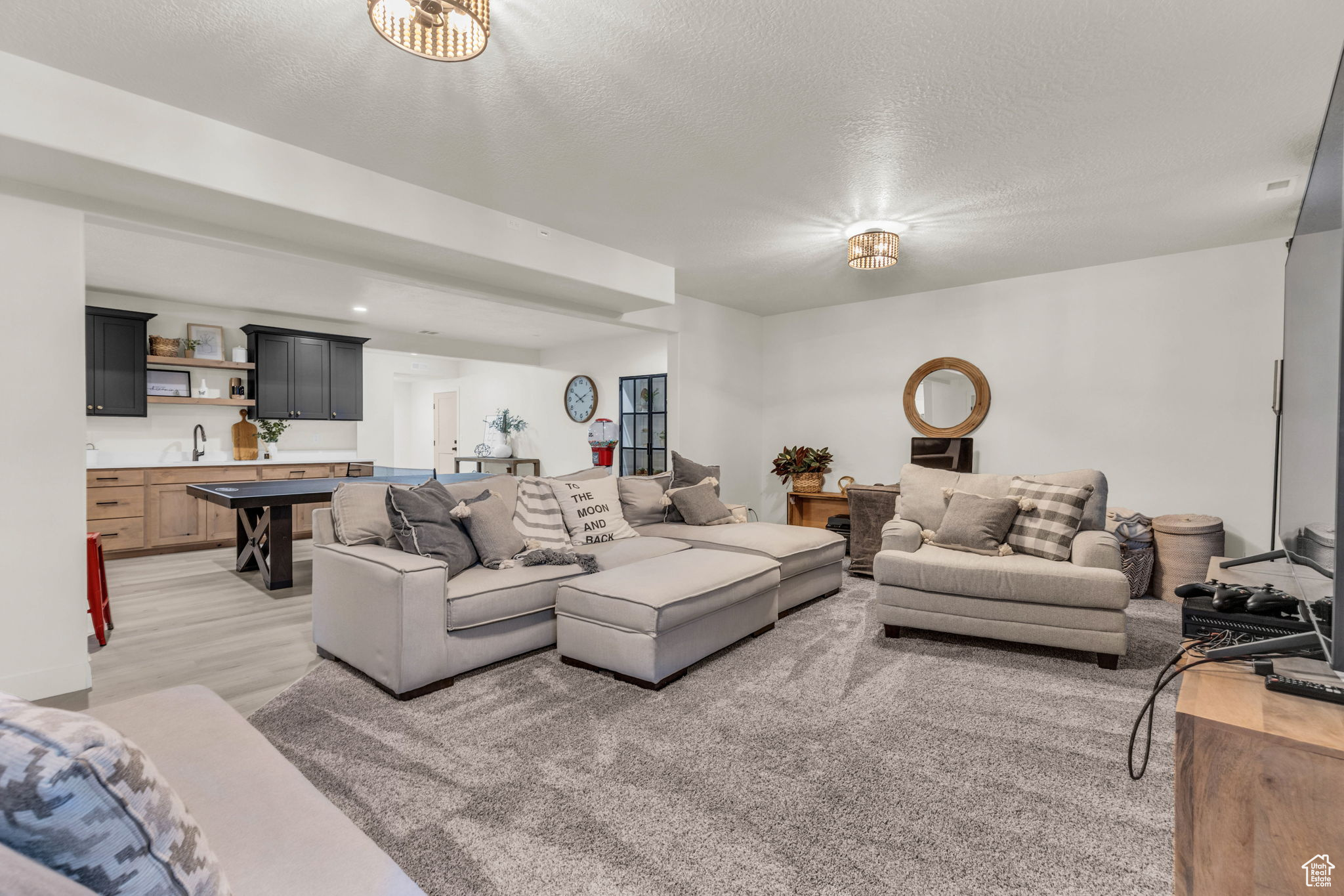 Living room with light hardwood / wood-style floors, wet bar, and a textured ceiling