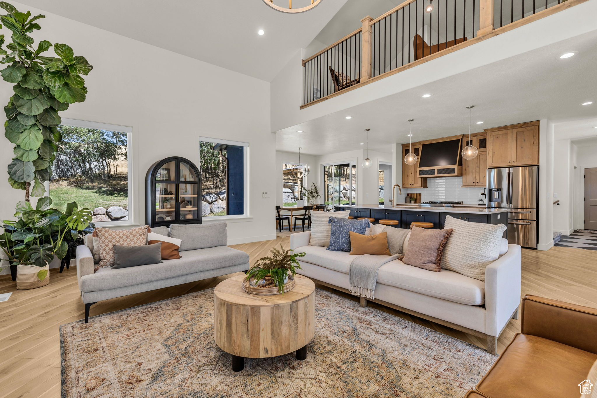 Living room with sink, light hardwood / wood-style floors, a high ceiling, and an inviting chandelier