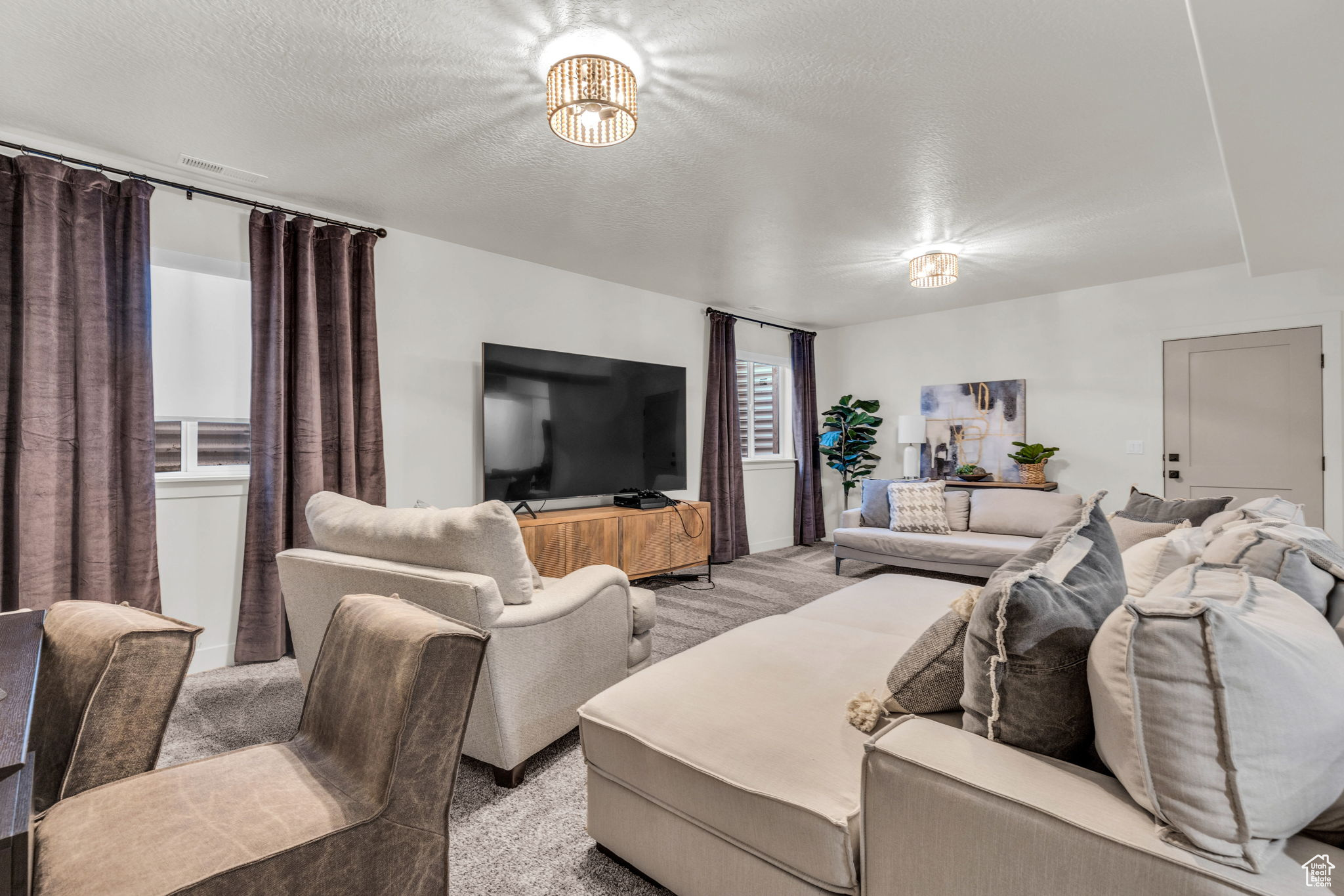 Living room featuring a notable chandelier, light colored carpet, and a textured ceiling