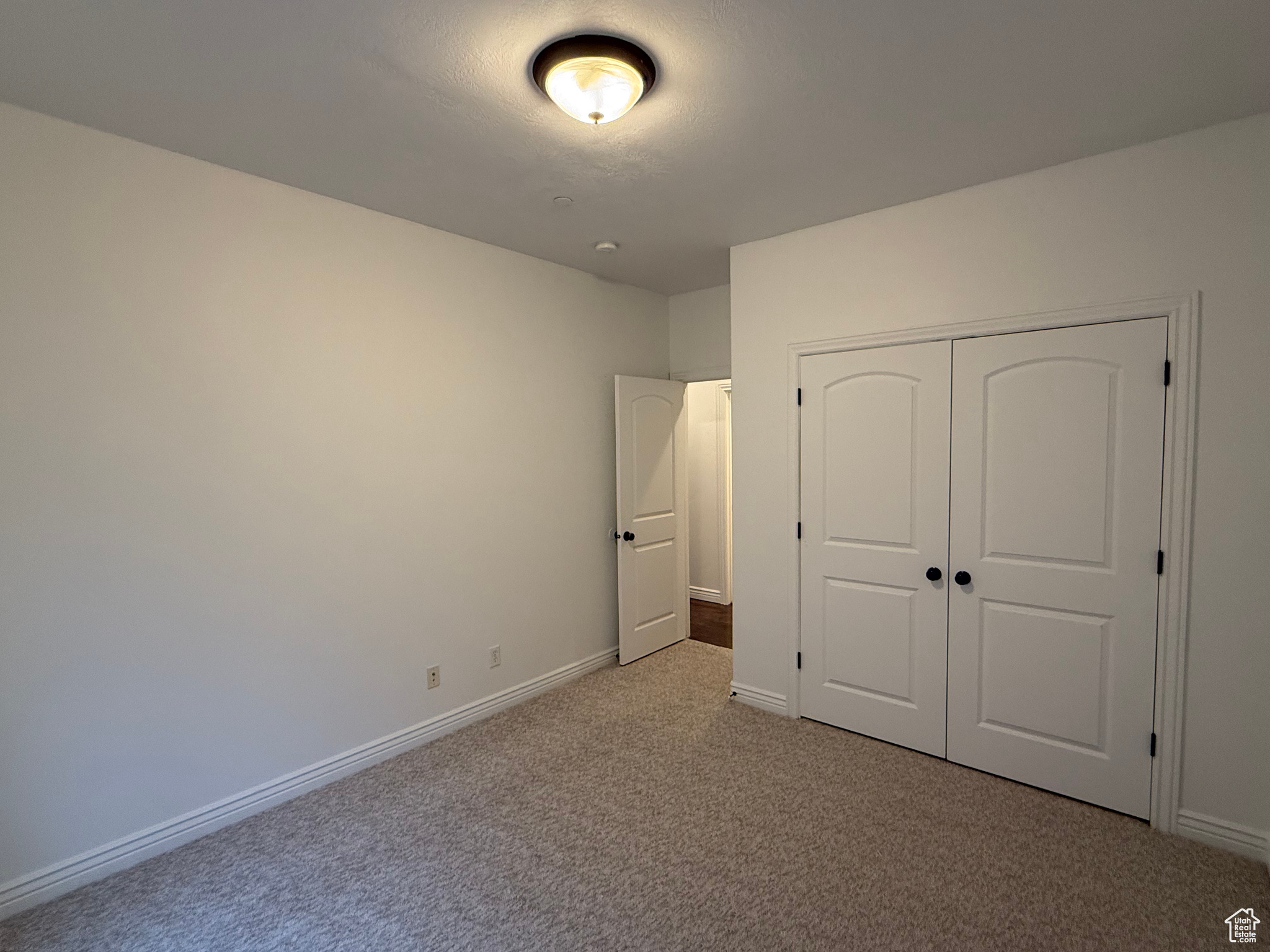 Unfurnished bedroom featuring light colored carpet and a closet