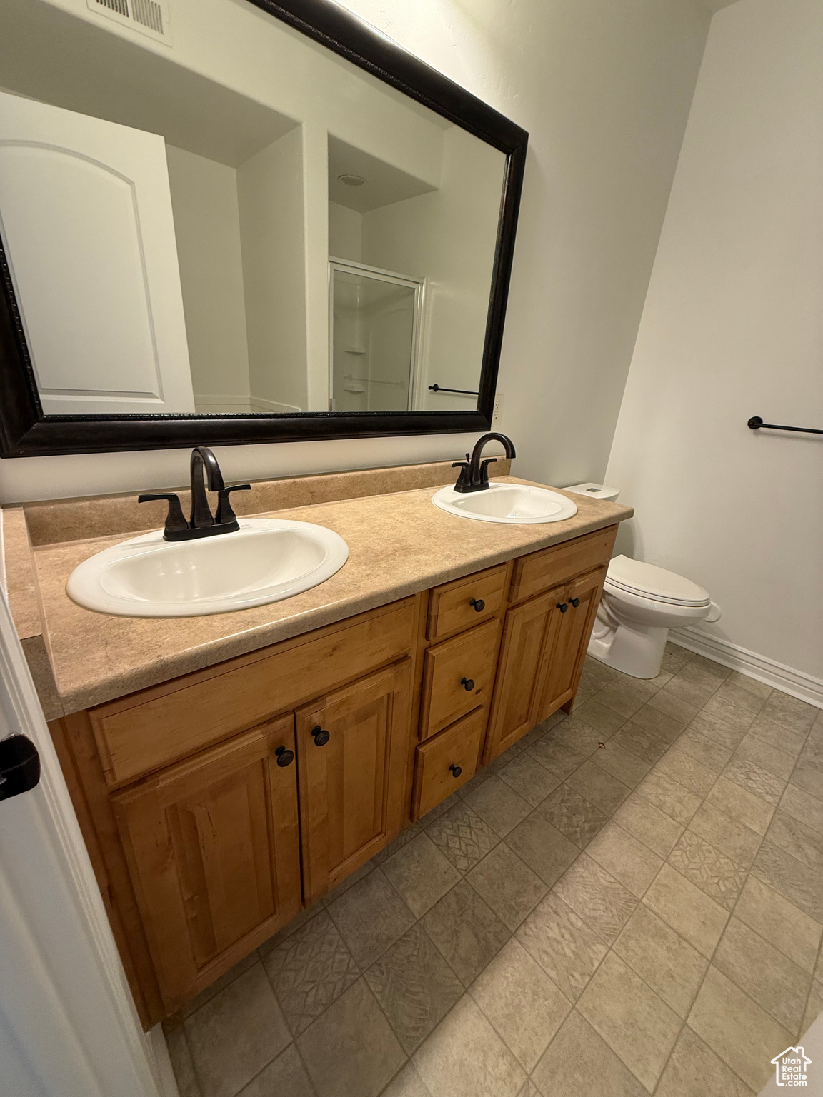 Bathroom with vanity, a shower with shower door, and toilet