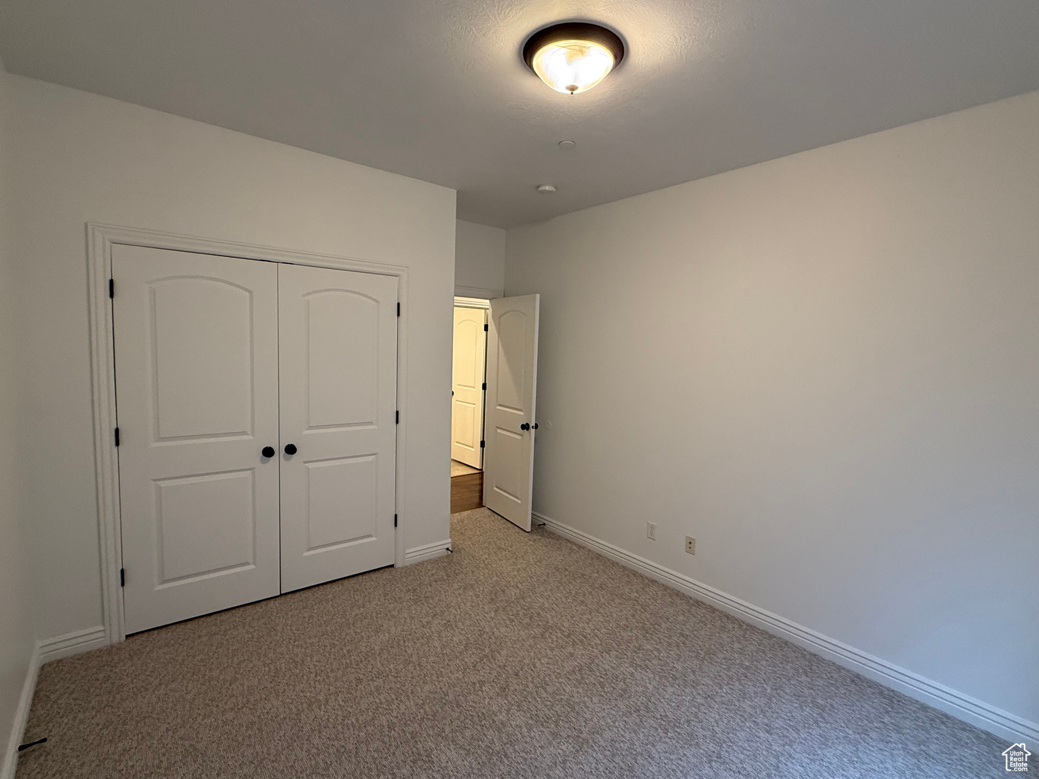 Unfurnished bedroom featuring light carpet and a closet