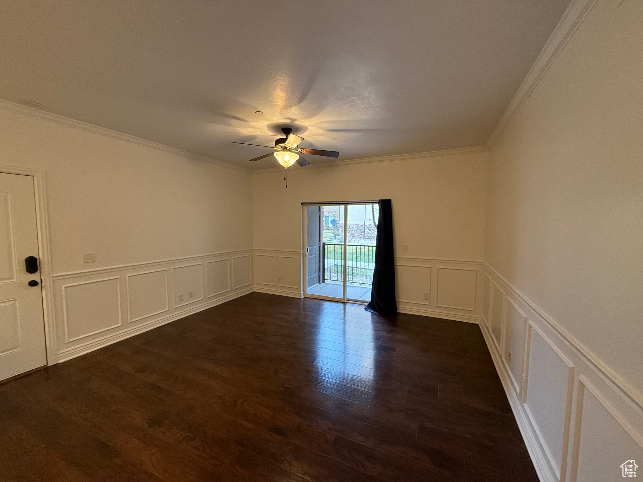 Empty room with dark hardwood / wood-style flooring, ceiling fan, and ornamental molding