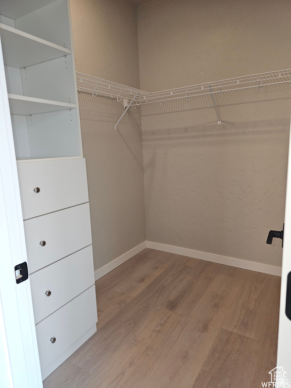 Walk in closet with wood-type flooring