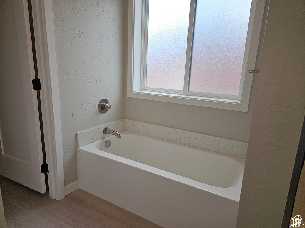 Bathroom with hardwood / wood-style floors and a tub