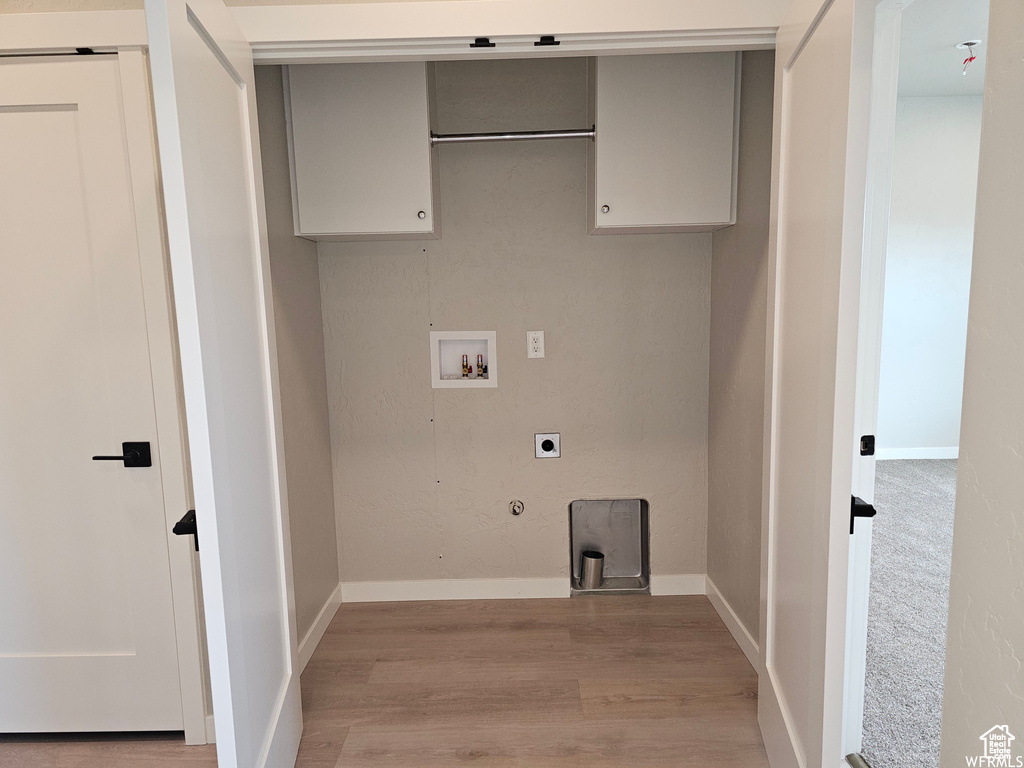 Washroom with electric dryer hookup, hookup for a gas dryer, hookup for a washing machine, and light hardwood / wood-style flooring