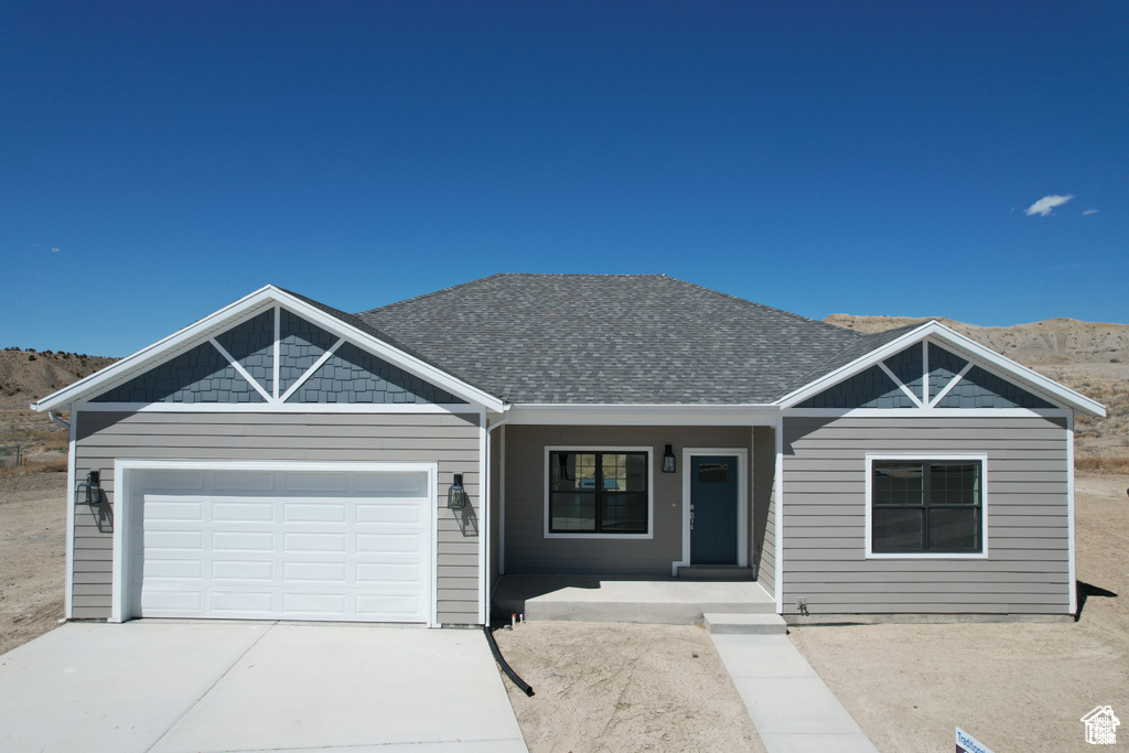 View of front of property featuring a mountain view, a porch, and a garage