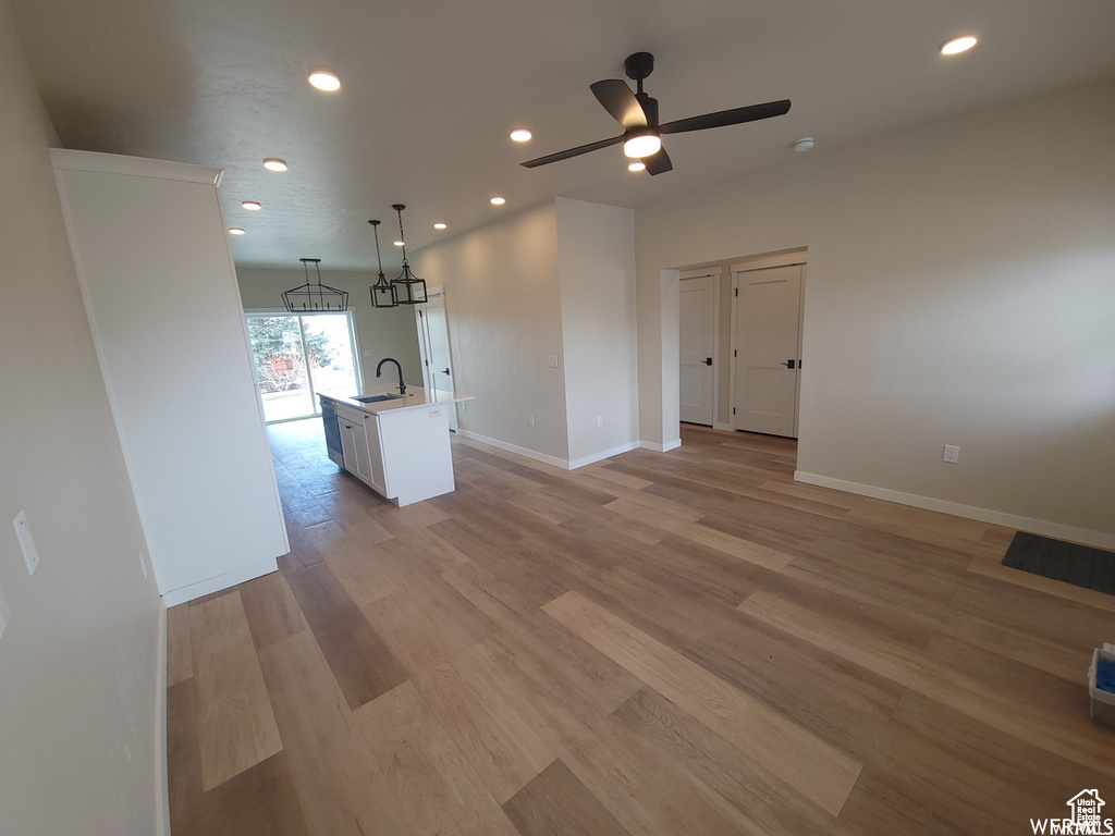 Unfurnished living room featuring ceiling fan, light hardwood / wood-style floors, and sink