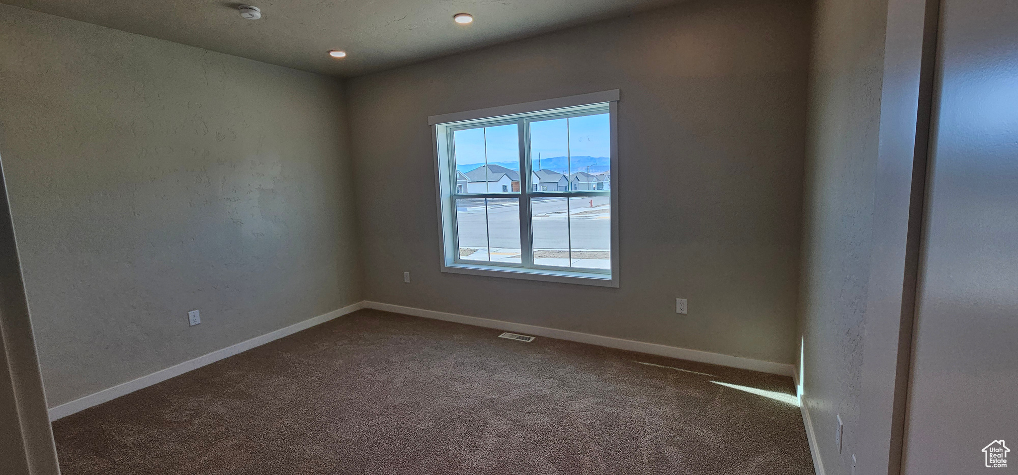 Spare room with a mountain view, a healthy amount of sunlight, and dark carpet