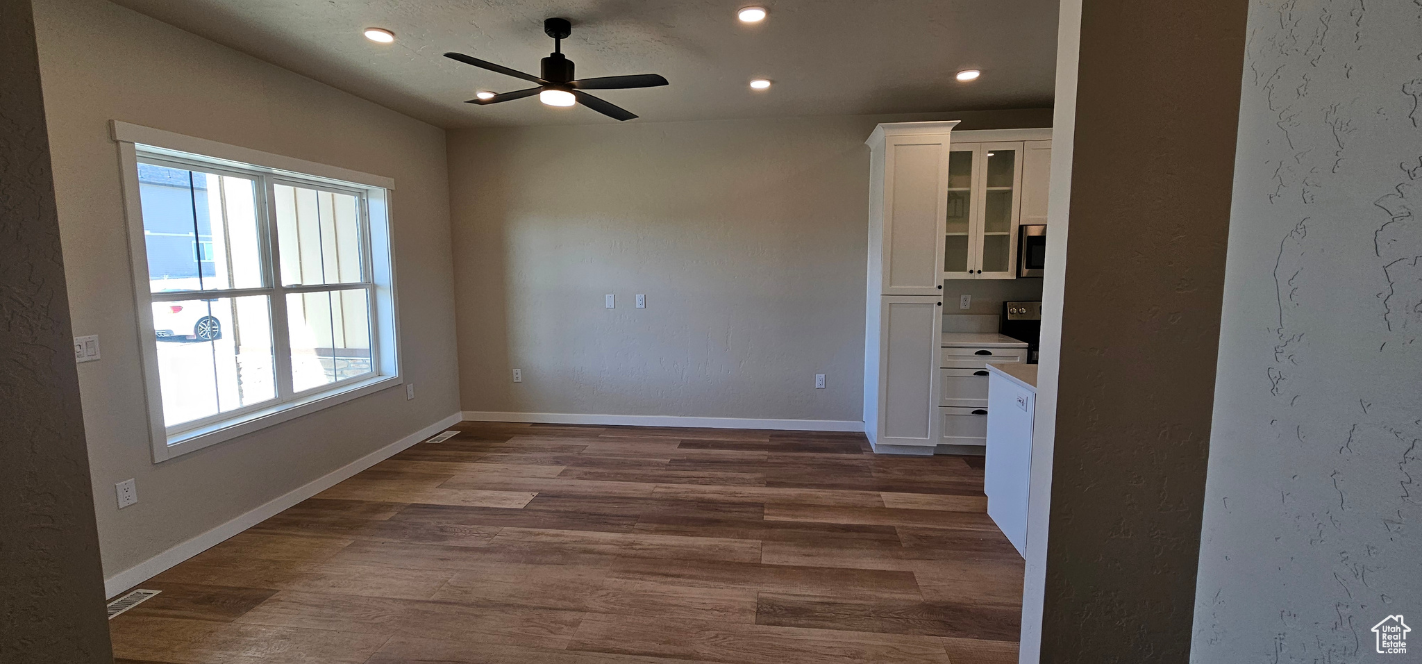 Empty room featuring ceiling fan and dark hardwood / wood-style floors