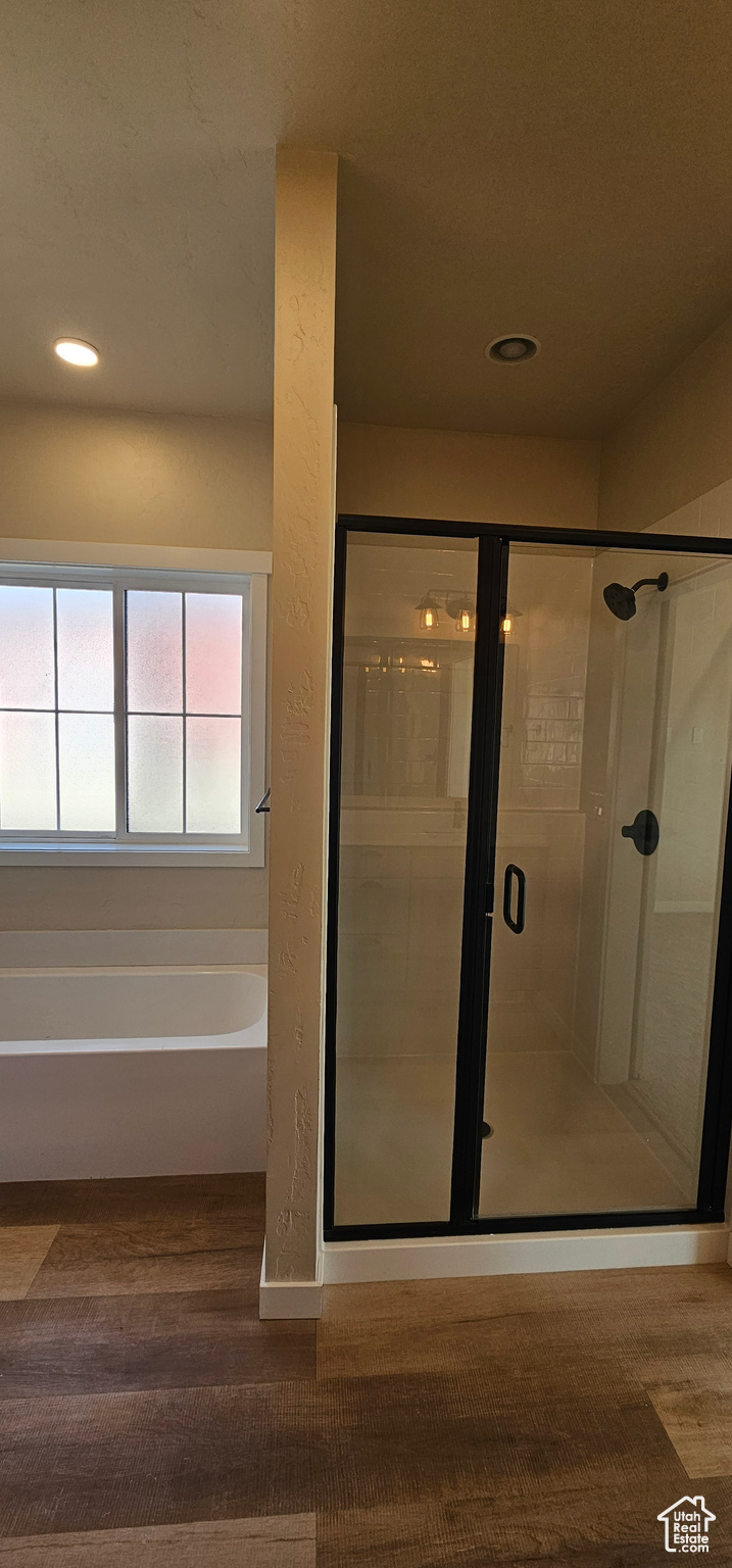 Bathroom with independent shower and bath and hardwood / wood-style flooring