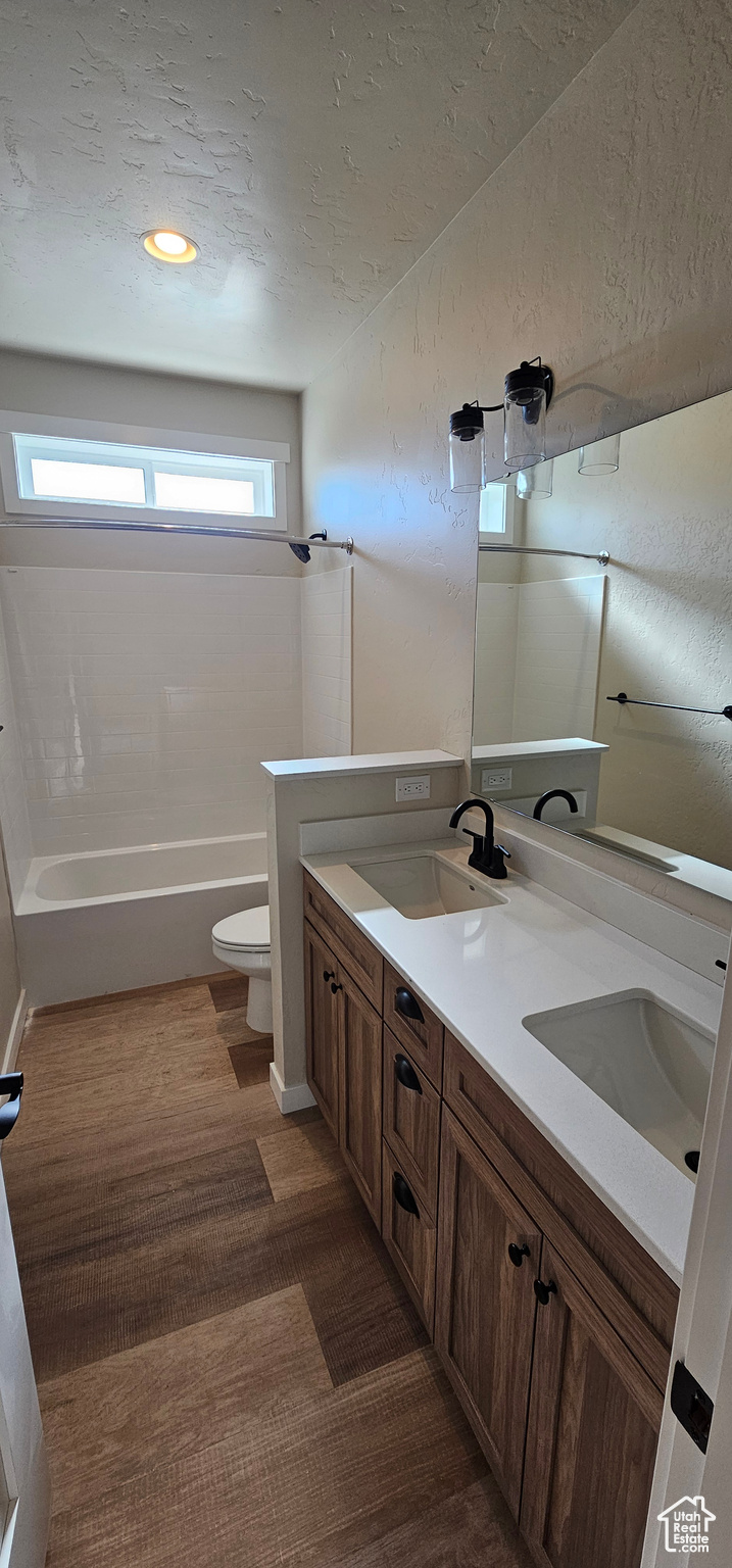 Full bathroom featuring shower / bathtub combination, vanity, a textured ceiling, hardwood / wood-style floors, and toilet