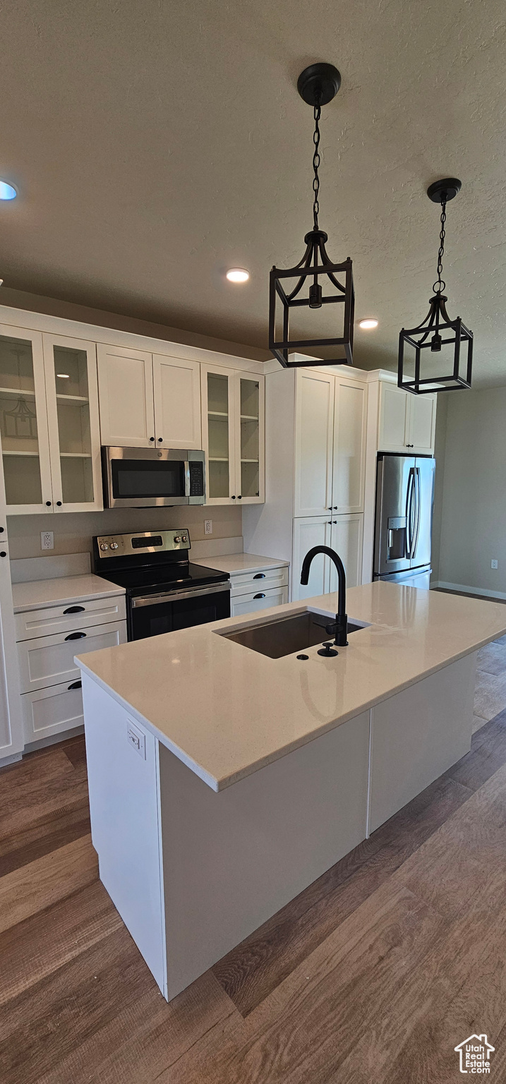 Kitchen featuring a center island with sink, white cabinets, stainless steel appliances, and sink