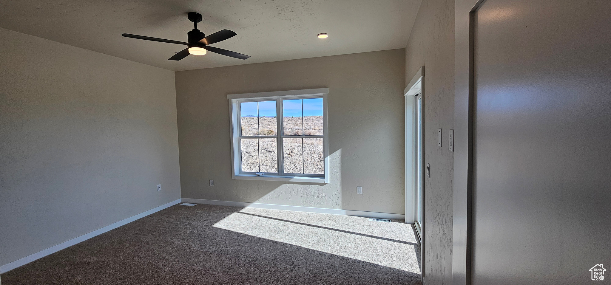 Spare room with dark colored carpet and ceiling fan