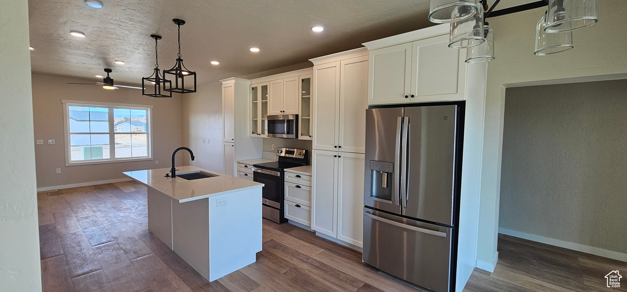 Kitchen featuring white cabinets, sink, ceiling fan, an island with sink, and stainless steel appliances