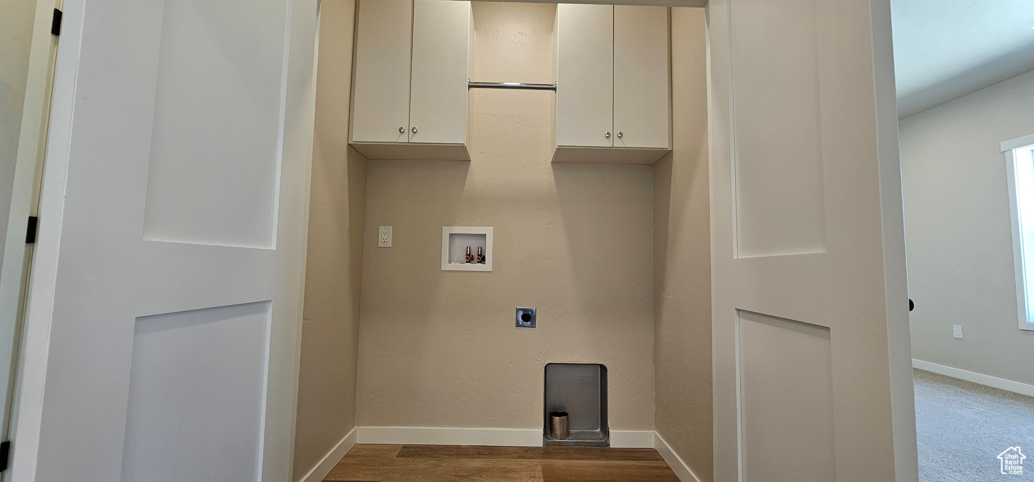 Clothes washing area featuring electric dryer hookup, cabinets, wood-type flooring, and hookup for a washing machine