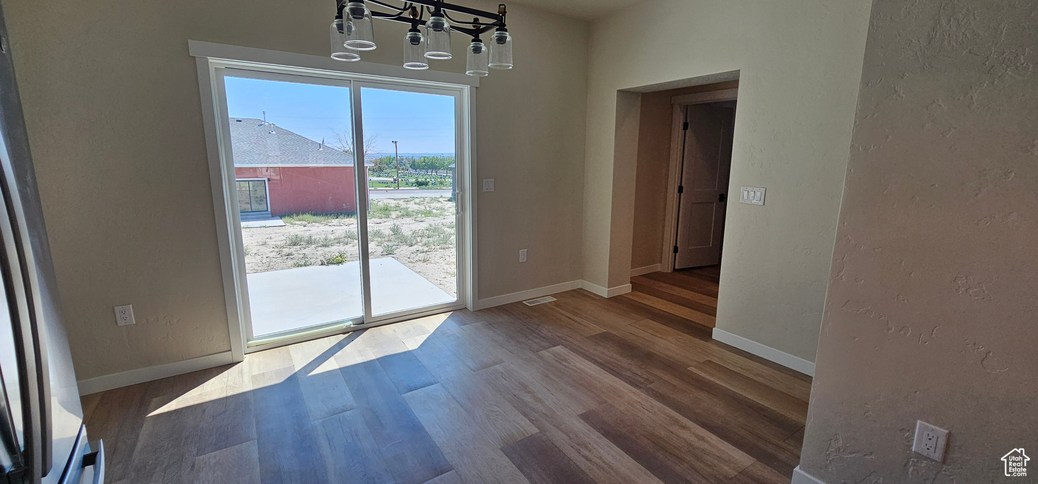 Unfurnished dining area with hardwood / wood-style floors and an inviting chandelier