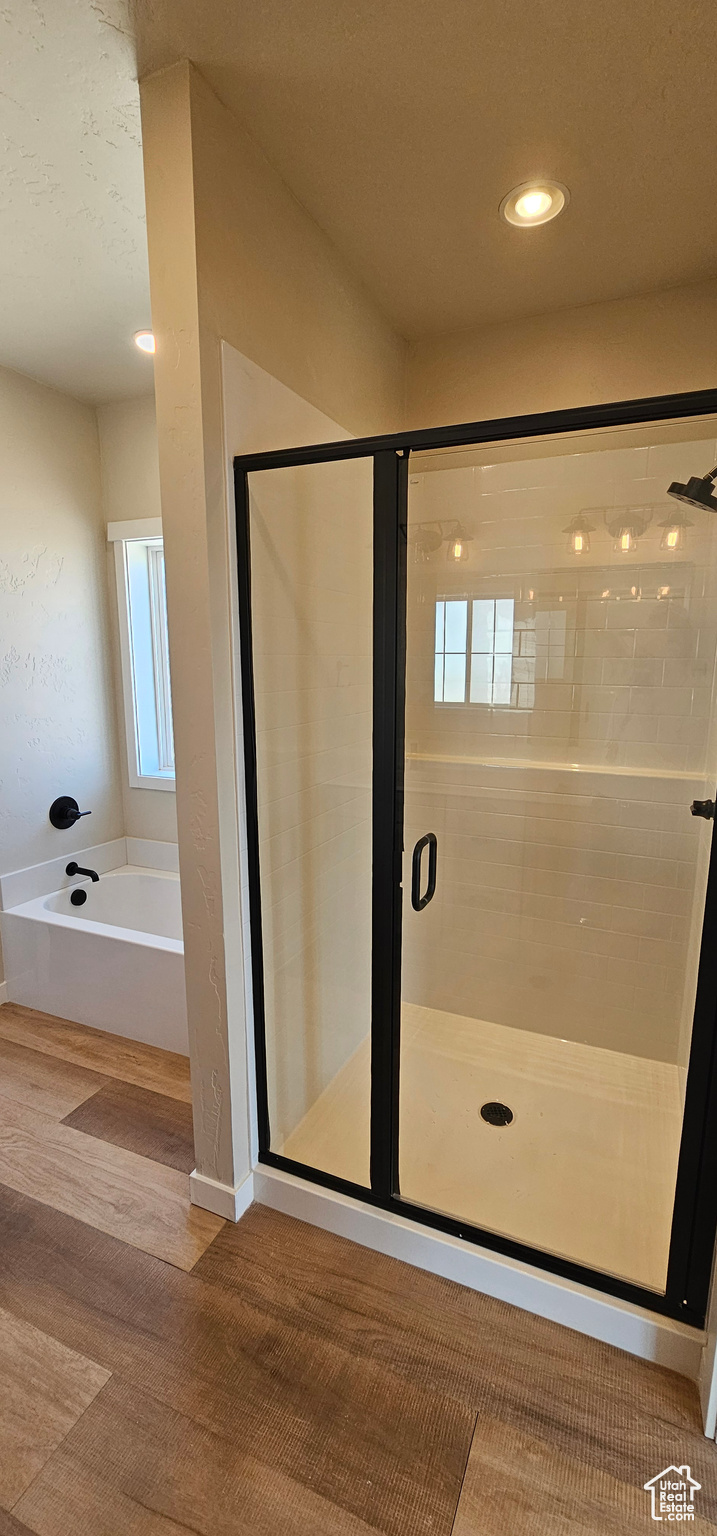 Bathroom featuring wood-type flooring and plus walk in shower