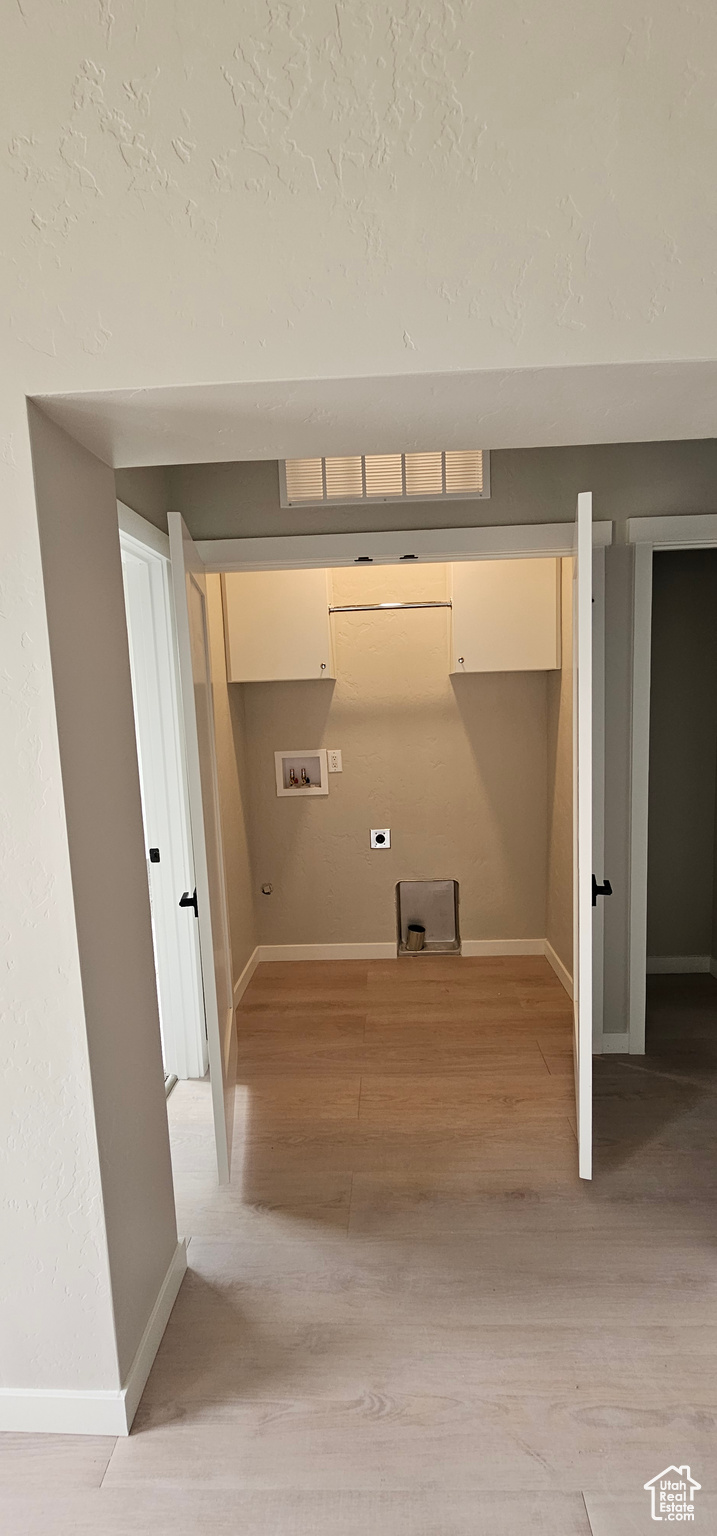 Laundry area with light hardwood / wood-style floors and hookup for a washing machine