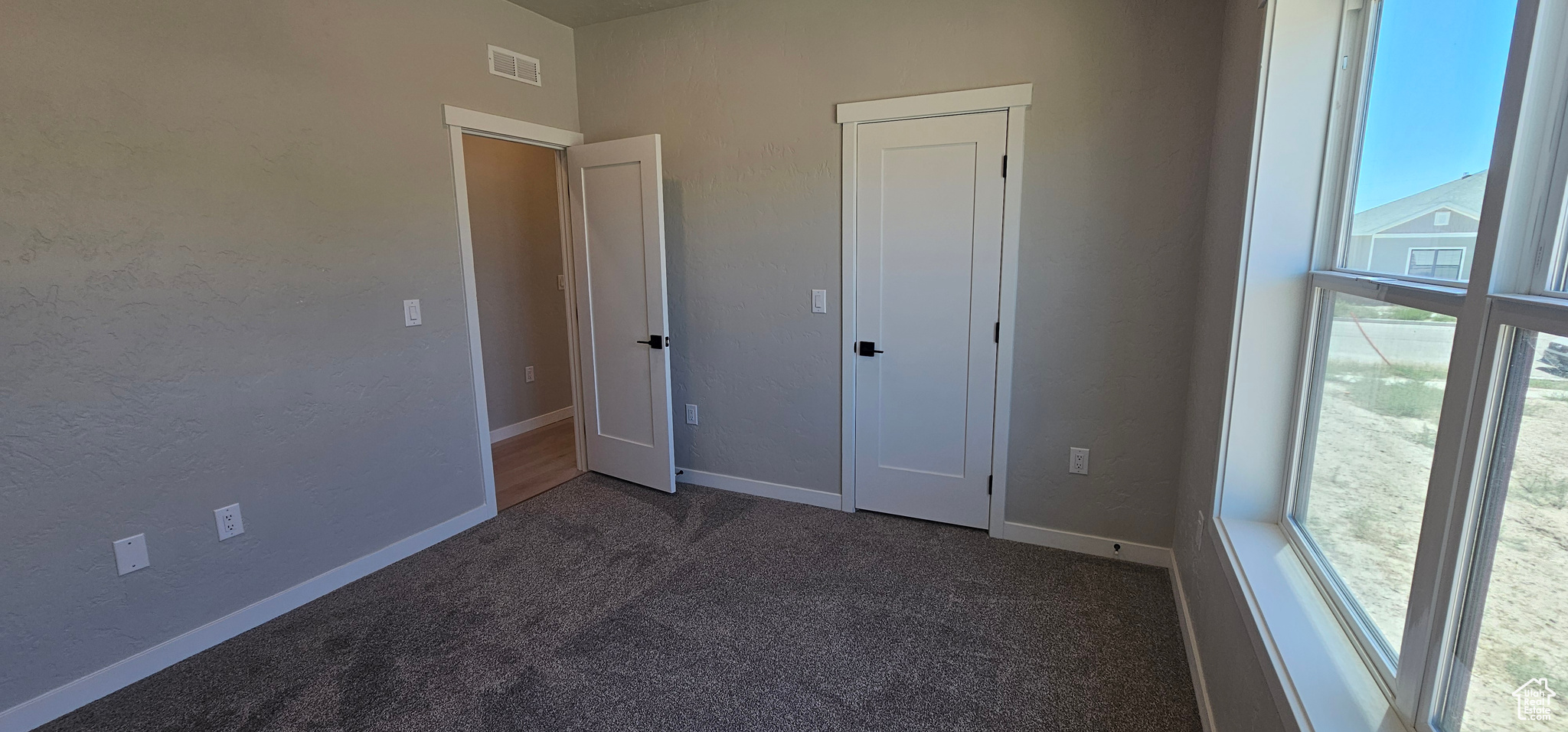 Unfurnished bedroom with dark colored carpet