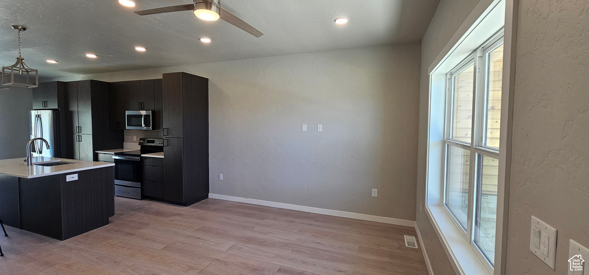 Kitchen with a wealth of natural light, sink, pendant lighting, and appliances with stainless steel finishes