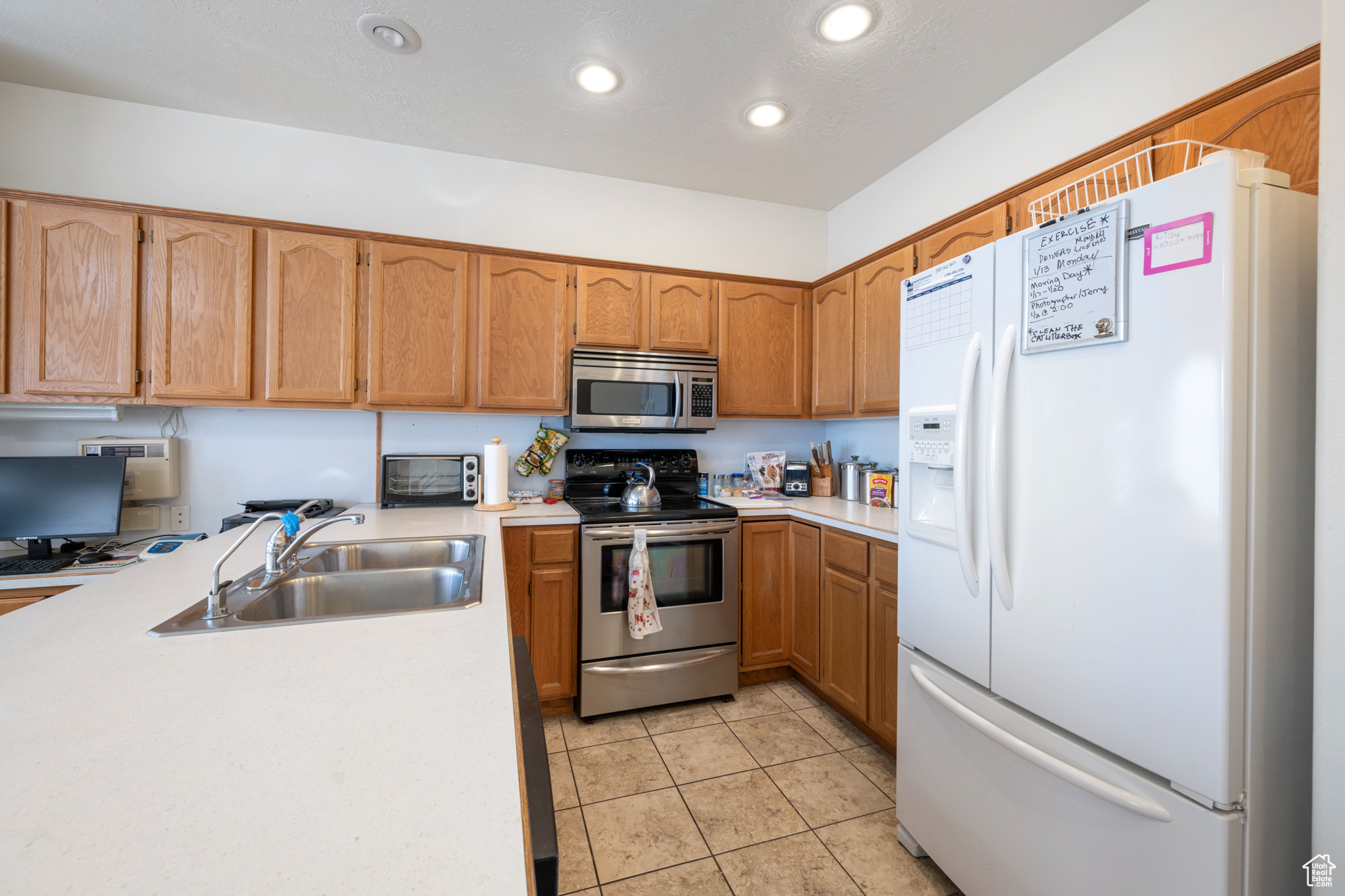 Kitchen featuring light tile patterned floors, sink, and appliances with stainless steel finishes