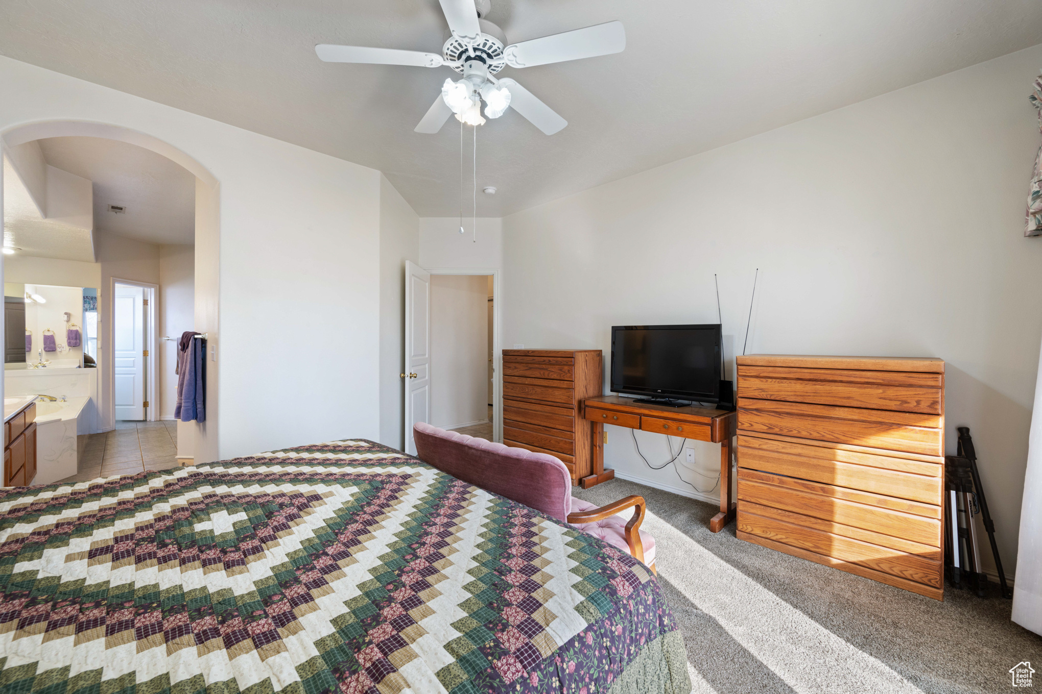 Carpeted bedroom with ensuite bathroom and ceiling fan