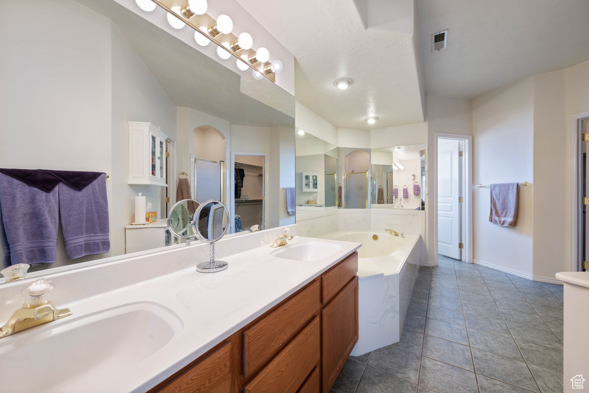 Bathroom featuring tile patterned floors, vanity, and plus walk in shower