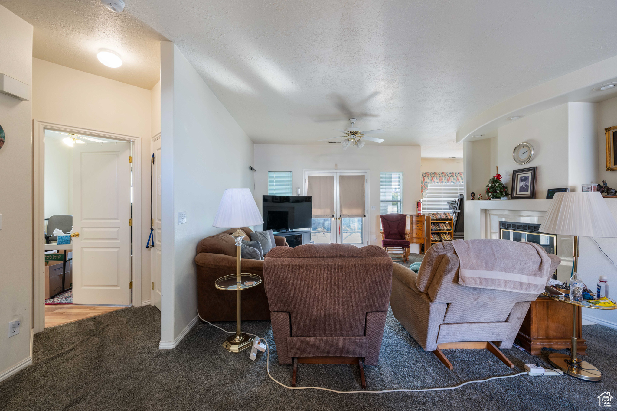 Carpeted living room with a textured ceiling and ceiling fan